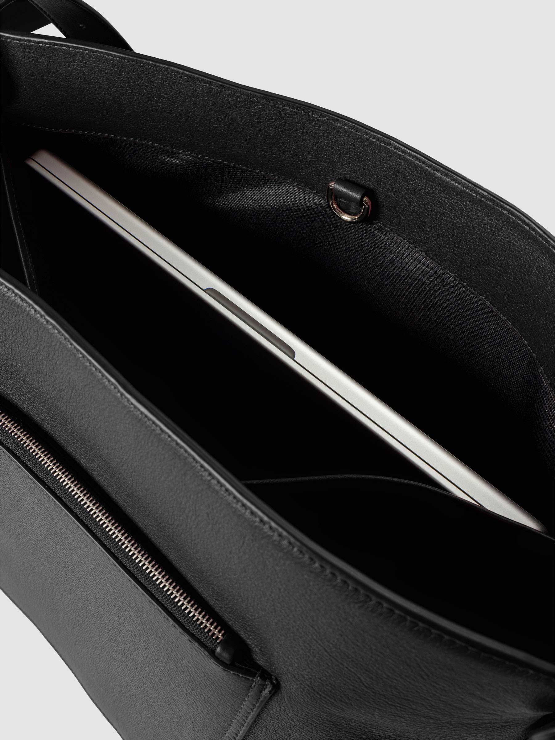 Detail view of a laptop inside the inner laptop pocket of The Metro Tote in the color Padrillo.