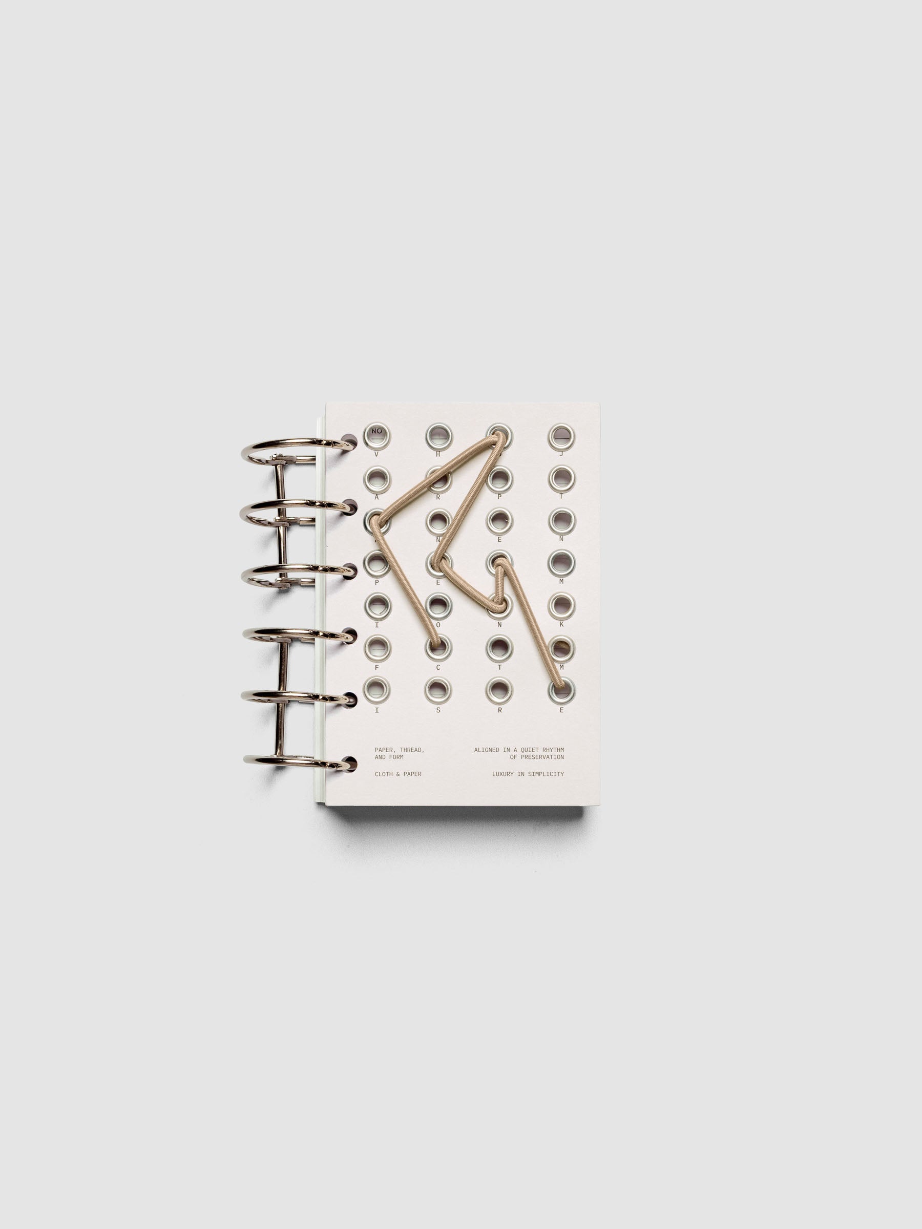 Cadence Dashboard with grommets and string on beige cardstock shown in size Pocket for 6-ring planners and notebooks.