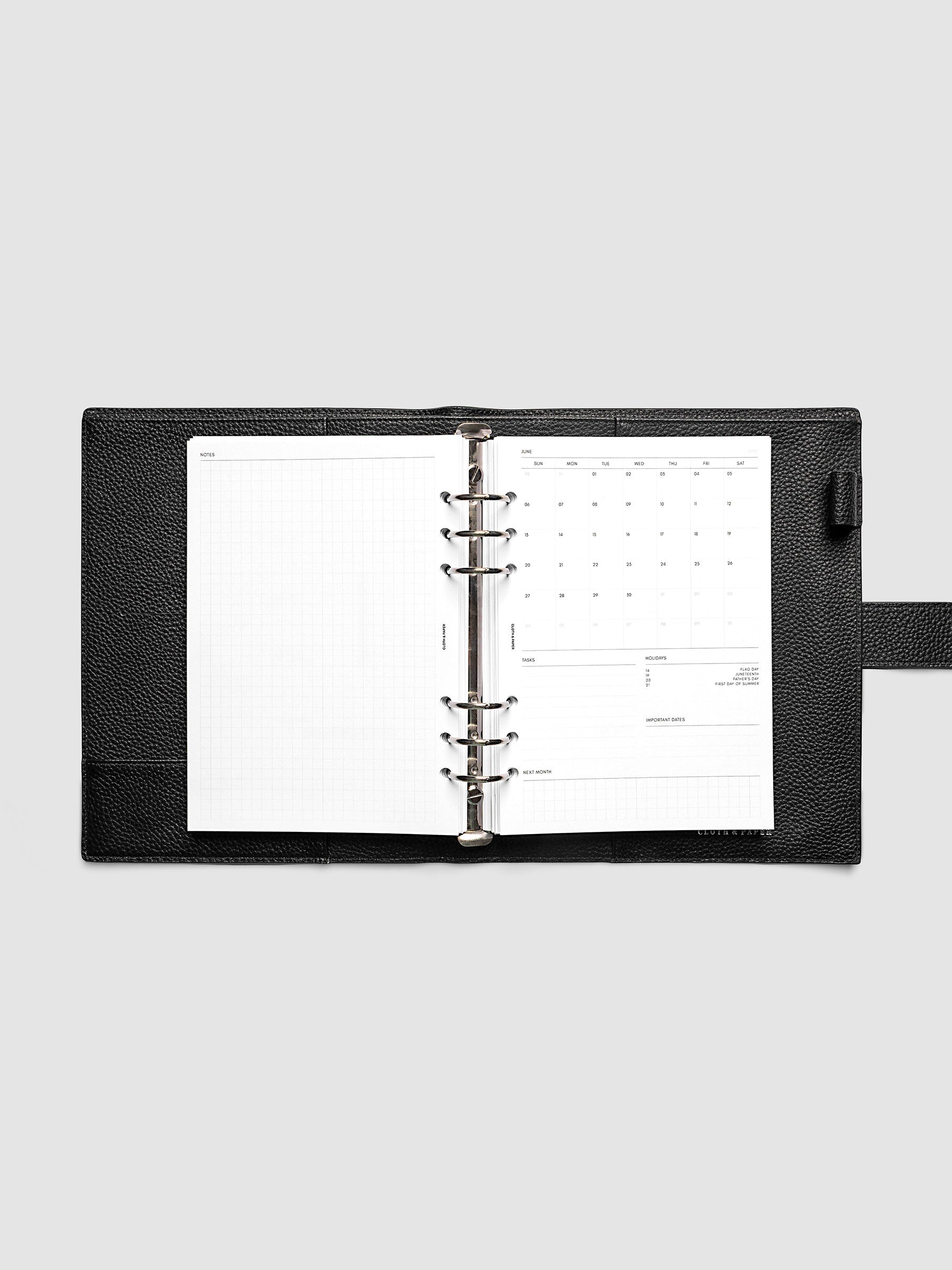 2027 Dated Monthly Admin Inserts open inside a A5 6-Ring Punch 6-ring planner, showing the fully open graph left page alongside the Sunday start monthly calendar, task section, holiday reference, important dates, and next month preview on the right.