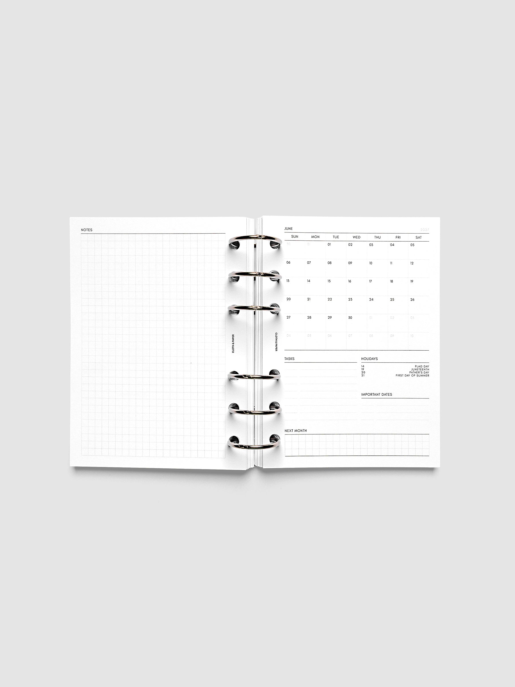 2027 Dated Monthly Admin Inserts open inside a A6 6-Ring Punch 6-ring planner, showing the fully open graph left page alongside the Sunday start monthly calendar, task section, holiday reference, important dates, and next month preview on the right.