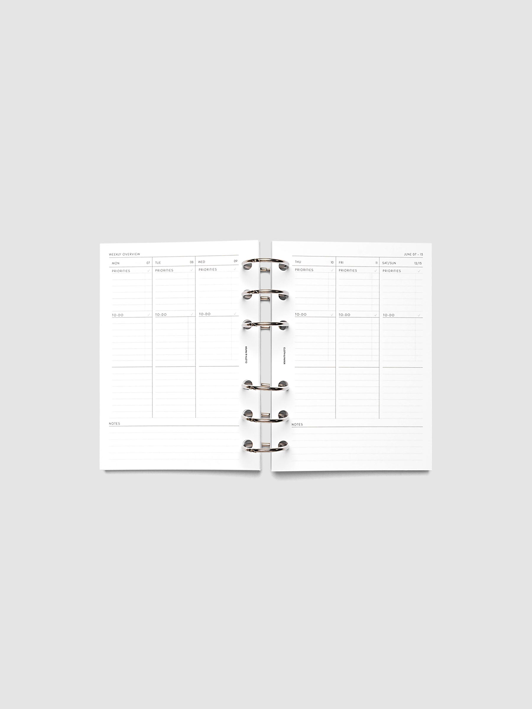 Both pages inside planner: 2027 Dated Weekly Task Planner Inserts, Monday Start, A6 6-Ring Punch, full week-on-two-pages spread showing blank vertical columns for each day with labeled priorities, to-do, and notes sections, Saturday and Sunday combined, and weekly notes section along the bottom, shown inside a planner