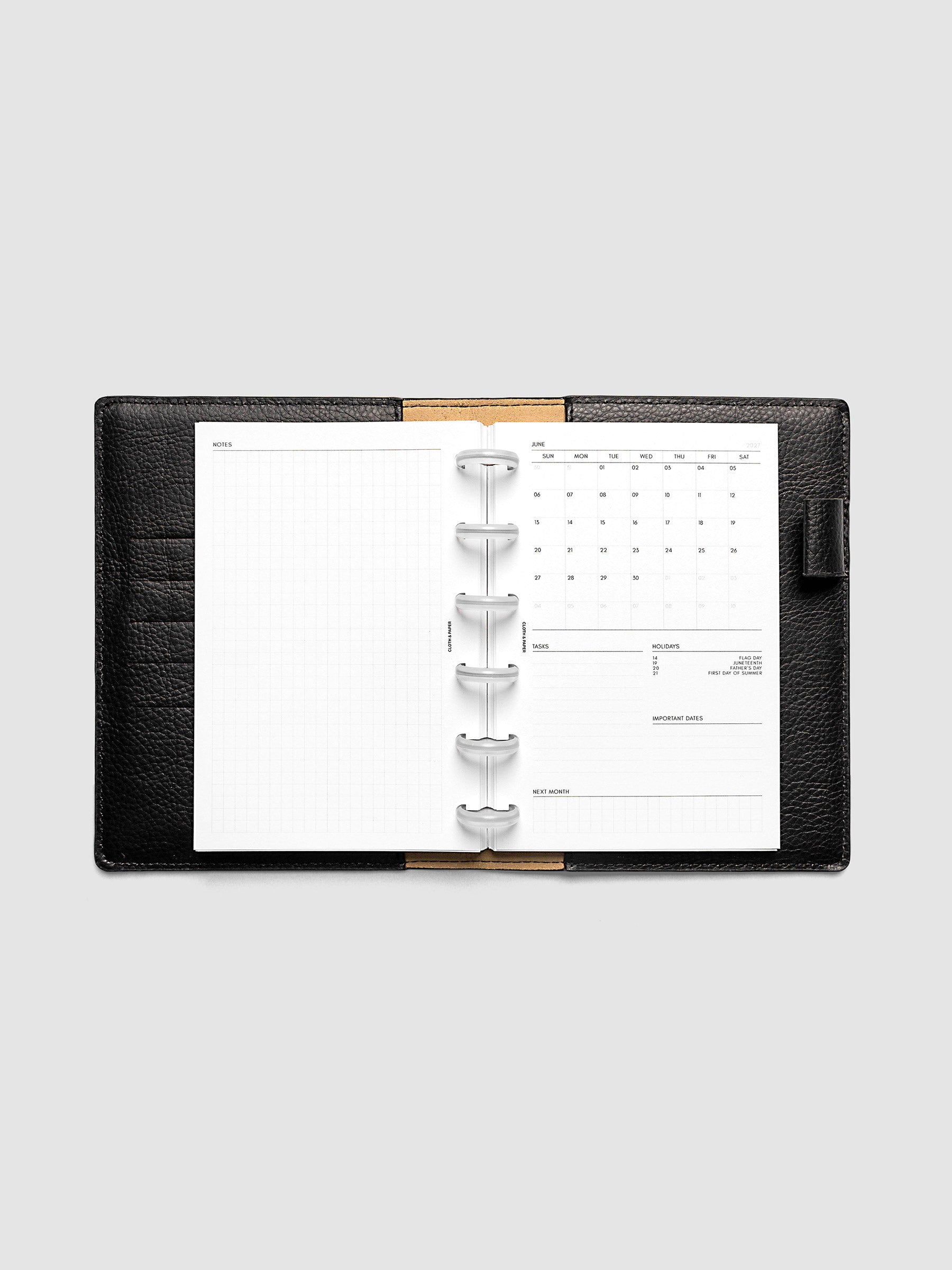 2027 Dated Monthly Admin Inserts open inside a CP Petite 6-Disc Punch discbound planner, showing the fully open graph left page alongside the Sunday start monthly calendar, task section, holiday reference, important dates, and next month preview on the right.