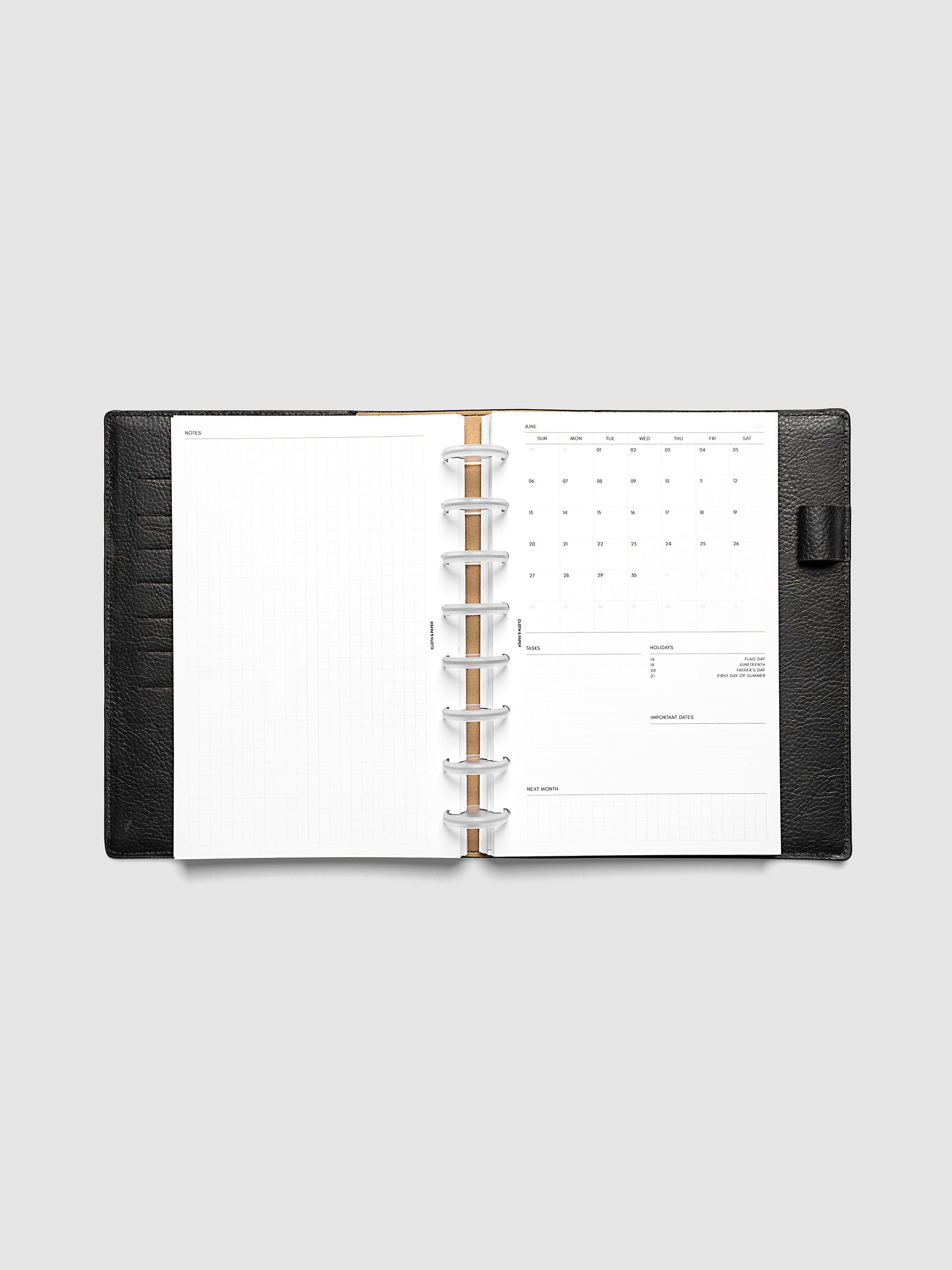 2027 Dated Monthly Admin Inserts open inside a Half Letter 8-Disc Punch discbound planner, showing the fully open graph left page alongside the Sunday start monthly calendar, task section, holiday reference, important dates, and next month preview on the right.
