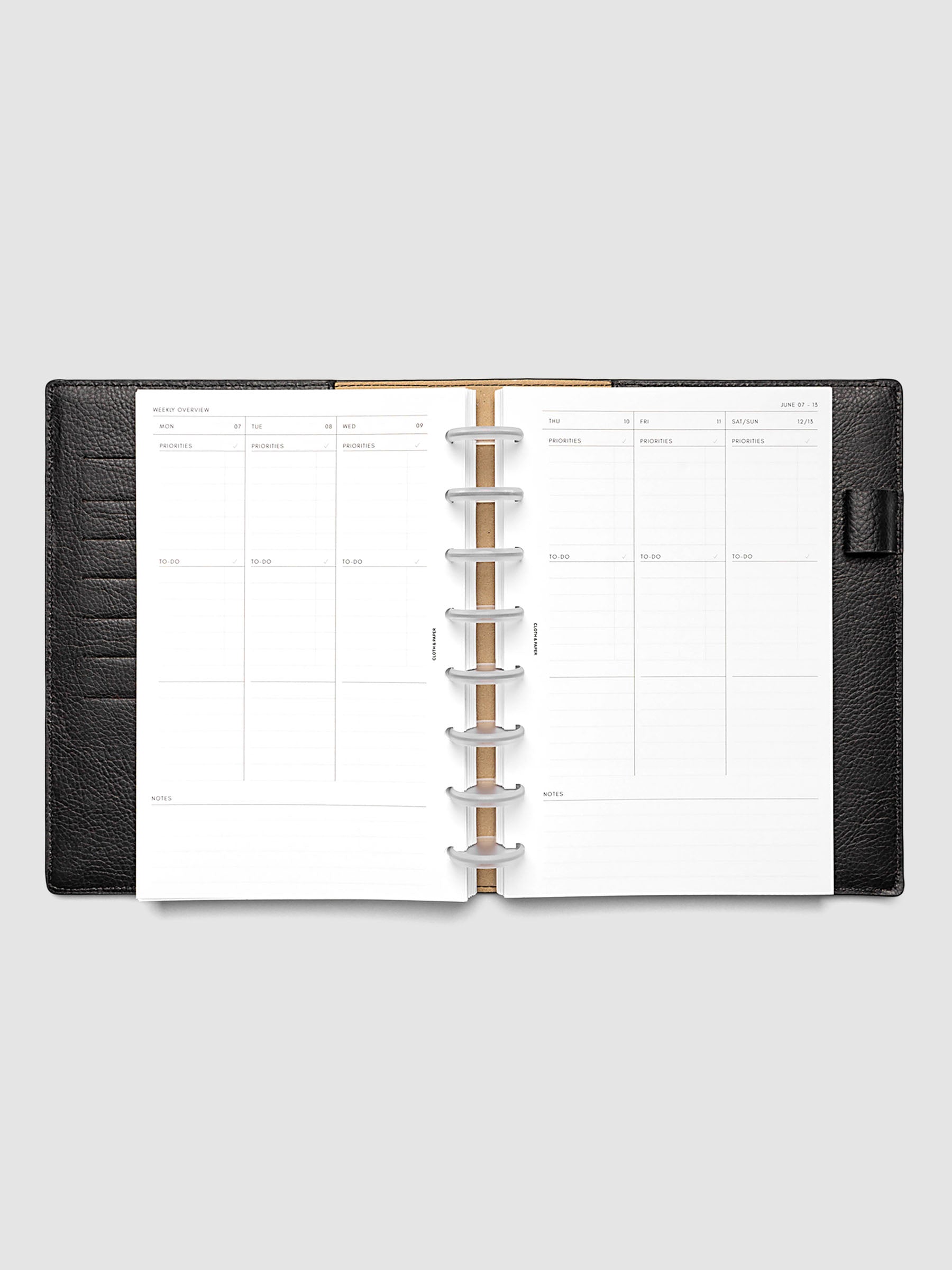 Both pages inside planner: 2027 Dated Weekly Task Planner Inserts, Monday Start, Half Letter 8-Disc Punch, full week-on-two-pages spread showing blank vertical columns for each day with labeled priorities, to-do, and notes sections, Saturday and Sunday combined, and weekly notes section along the bottom, shown inside a planner