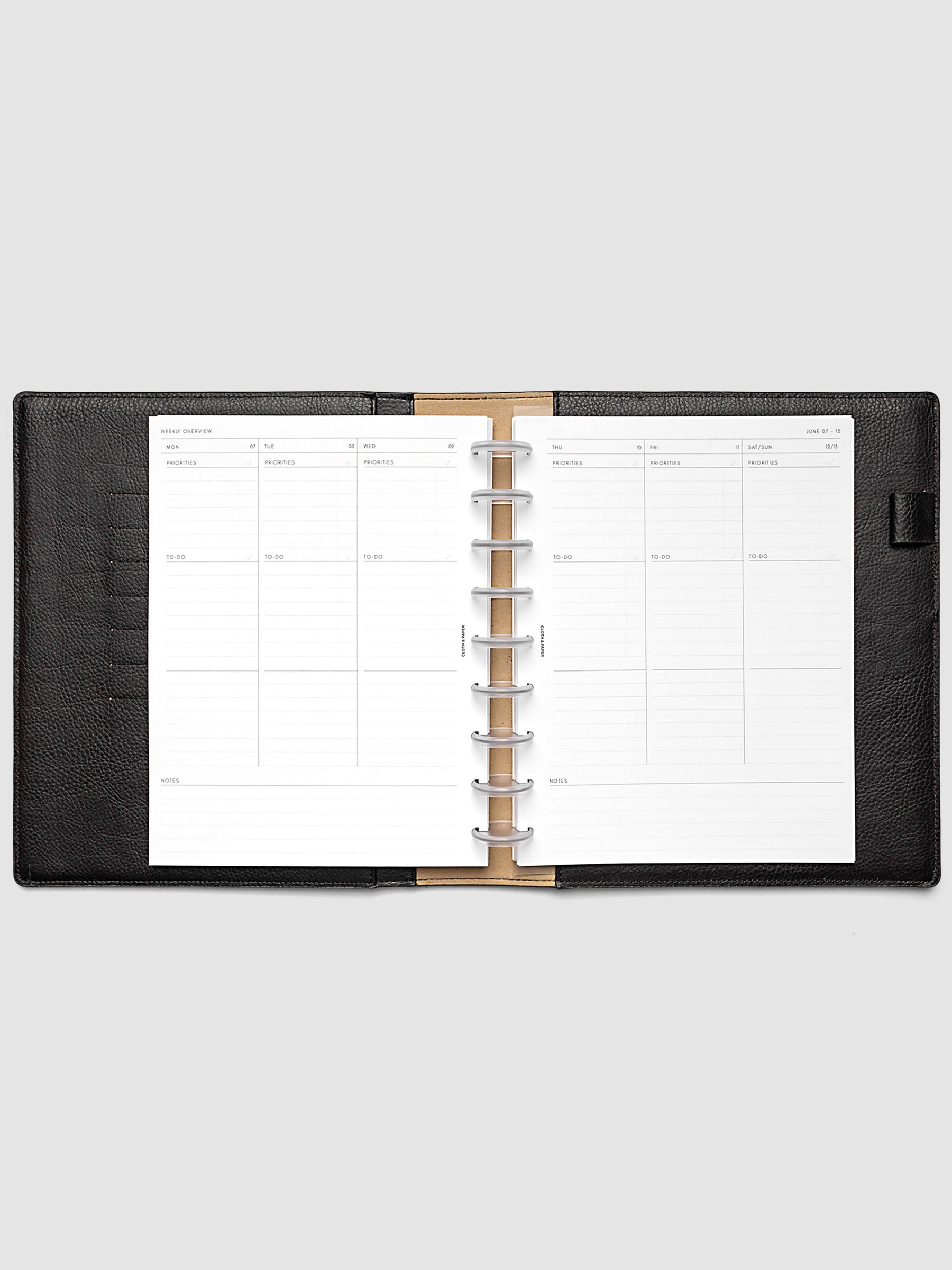 Both pages inside planner: 2027 Dated Weekly Task Planner Inserts, Monday Start, HP Classic 9-Disc Punch, full week-on-two-pages spread showing blank vertical columns for each day with labeled priorities, to-do, and notes sections, Saturday and Sunday combined, and weekly notes section along the bottom, shown inside a planner