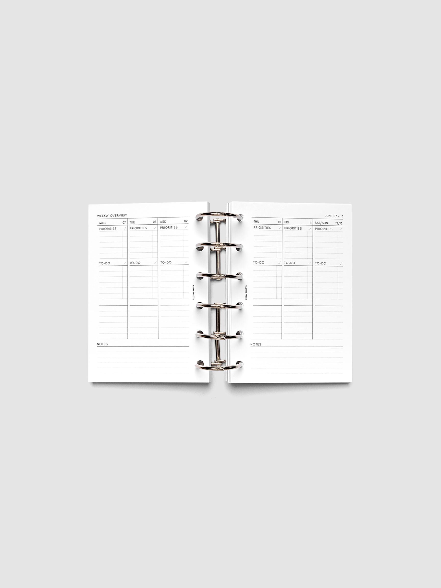 Both pages inside planner: 2027 Dated Weekly Task Planner Inserts, Monday Start, Pocket 6-Ring Punch, full week-on-two-pages spread showing blank vertical columns for each day with labeled priorities, to-do, and notes sections, Saturday and Sunday combined, and weekly notes section along the bottom, shown inside a planner