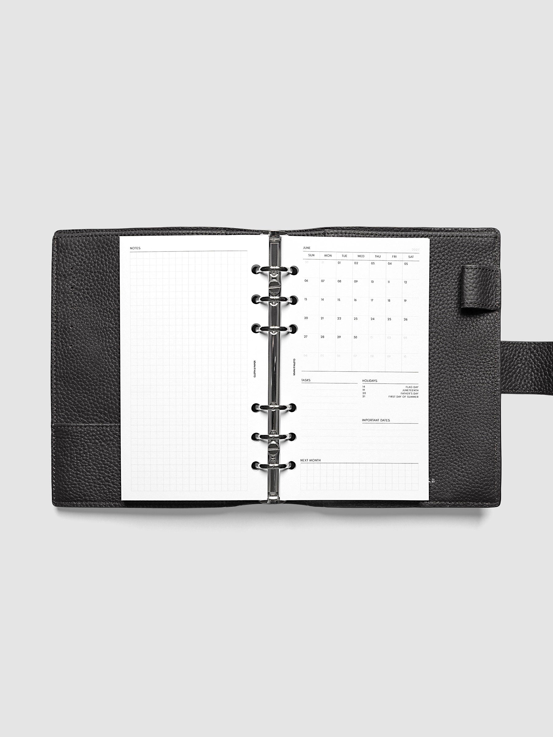2027 Dated Monthly Admin Inserts open inside a Personal 6-Ring Punch 6-ring planner, showing the fully open graph left page alongside the Sunday start monthly calendar, task section, holiday reference, important dates, and next month preview on the right.