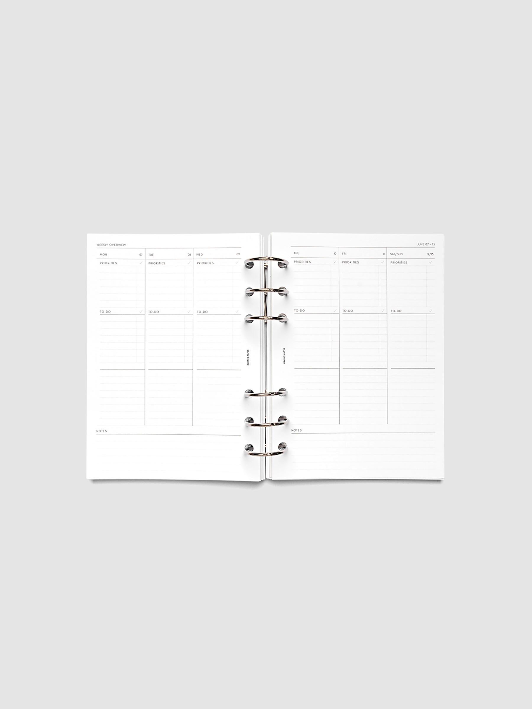 Both pages inside planner: 2027 Dated Weekly Task Planner Inserts, Monday Start, Personal Wide 6-Ring Punch, full week-on-two-pages spread showing blank vertical columns for each day with labeled priorities, to-do, and notes sections, Saturday and Sunday combined, and weekly notes section along the bottom, shown inside a planner
