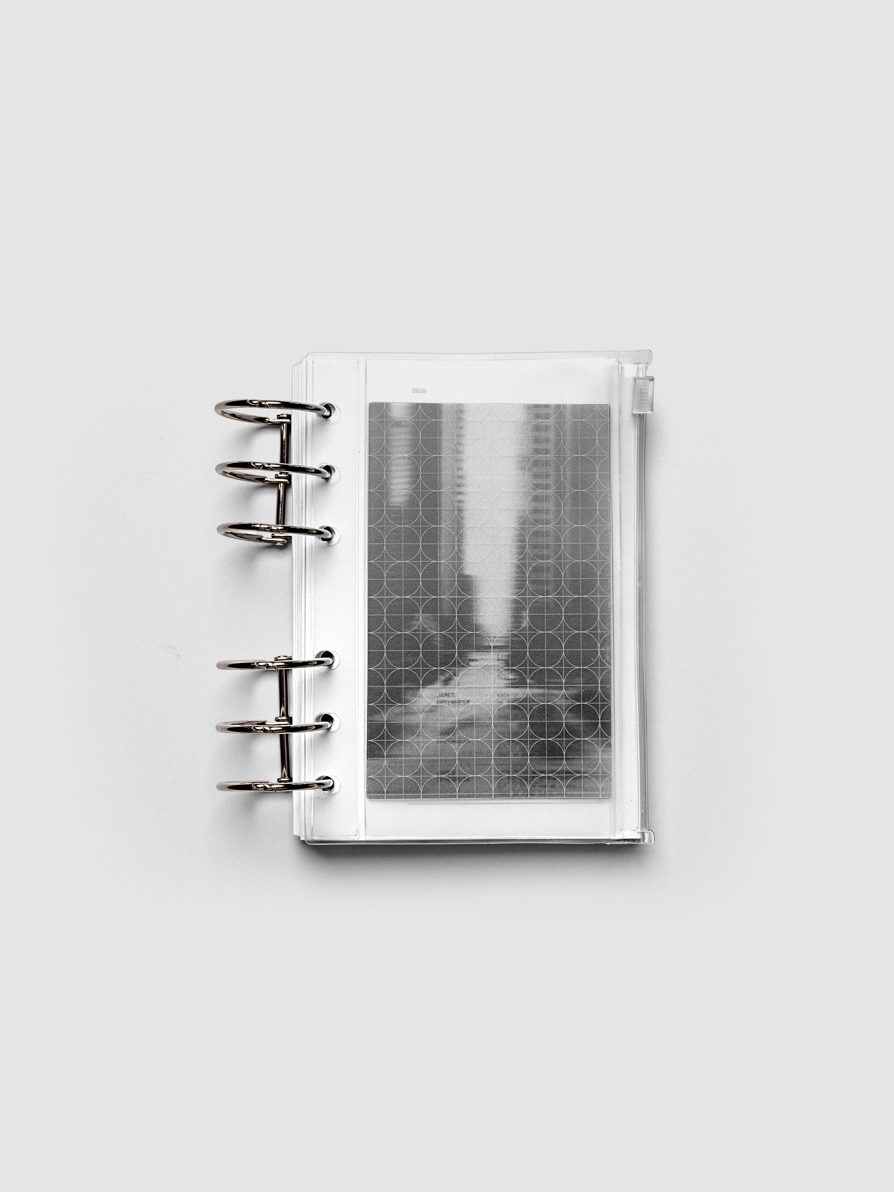 Side zipper transparent storage pouch for planners with decorative inner graph and photograph layers shown ring bound in size A6.