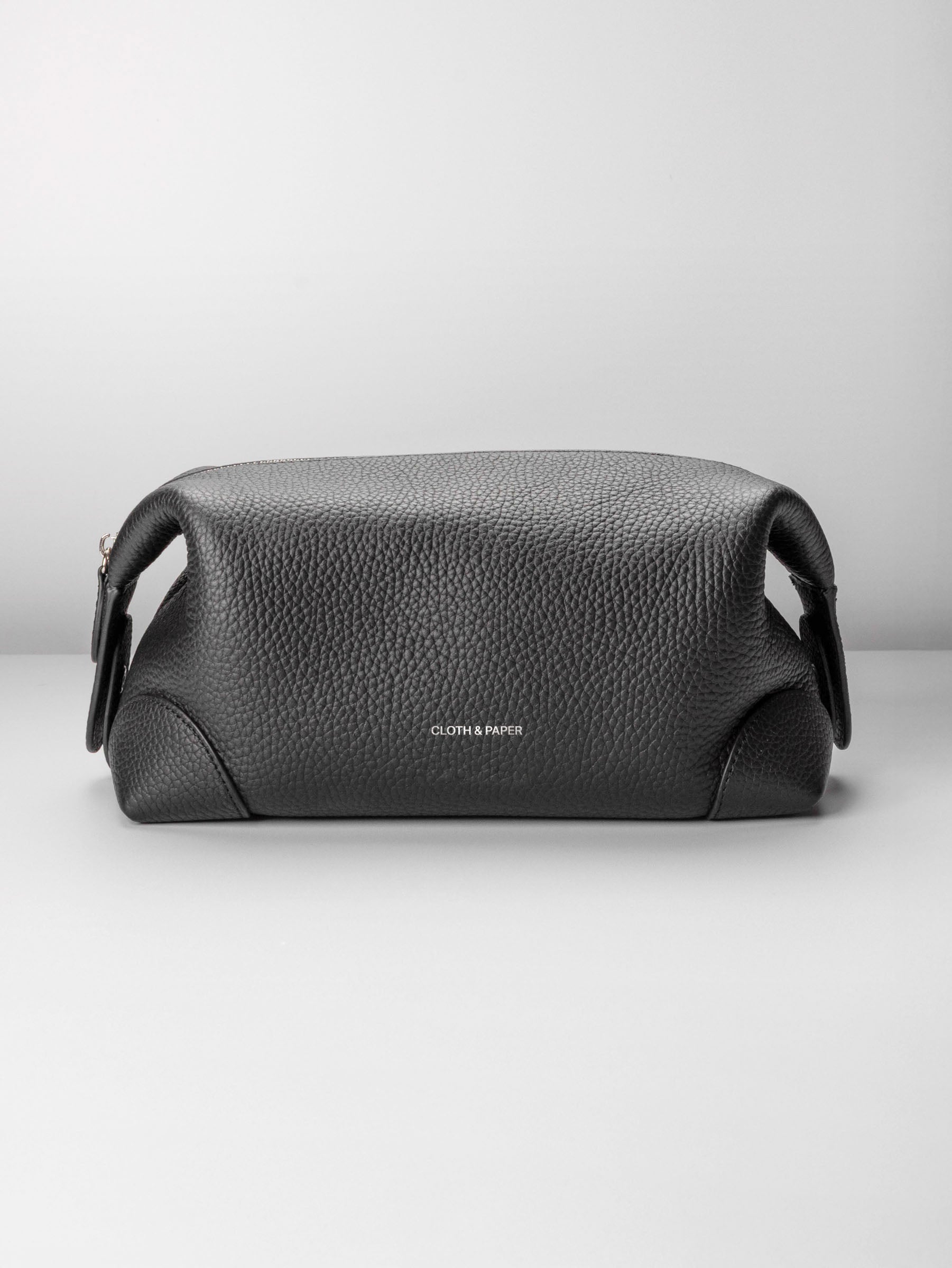 Folded Form Pouch in black pebbled leather, front view, snapped closed with silver foil Cloth & Paper logo centered on exterior