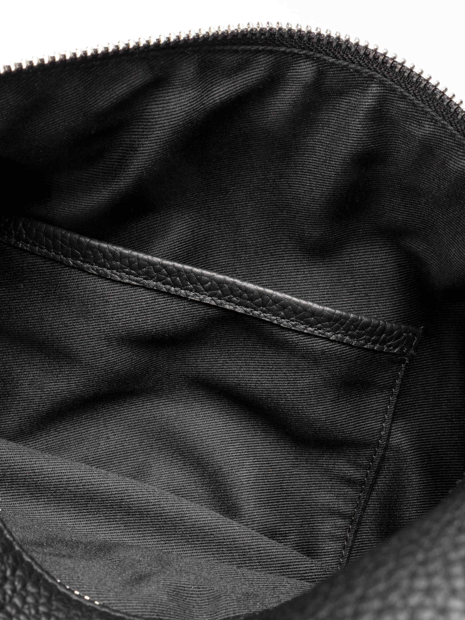 Folded Form Pouch close-up of silver snap hardware on side panel with leather zipper pull and silver zipper visible above