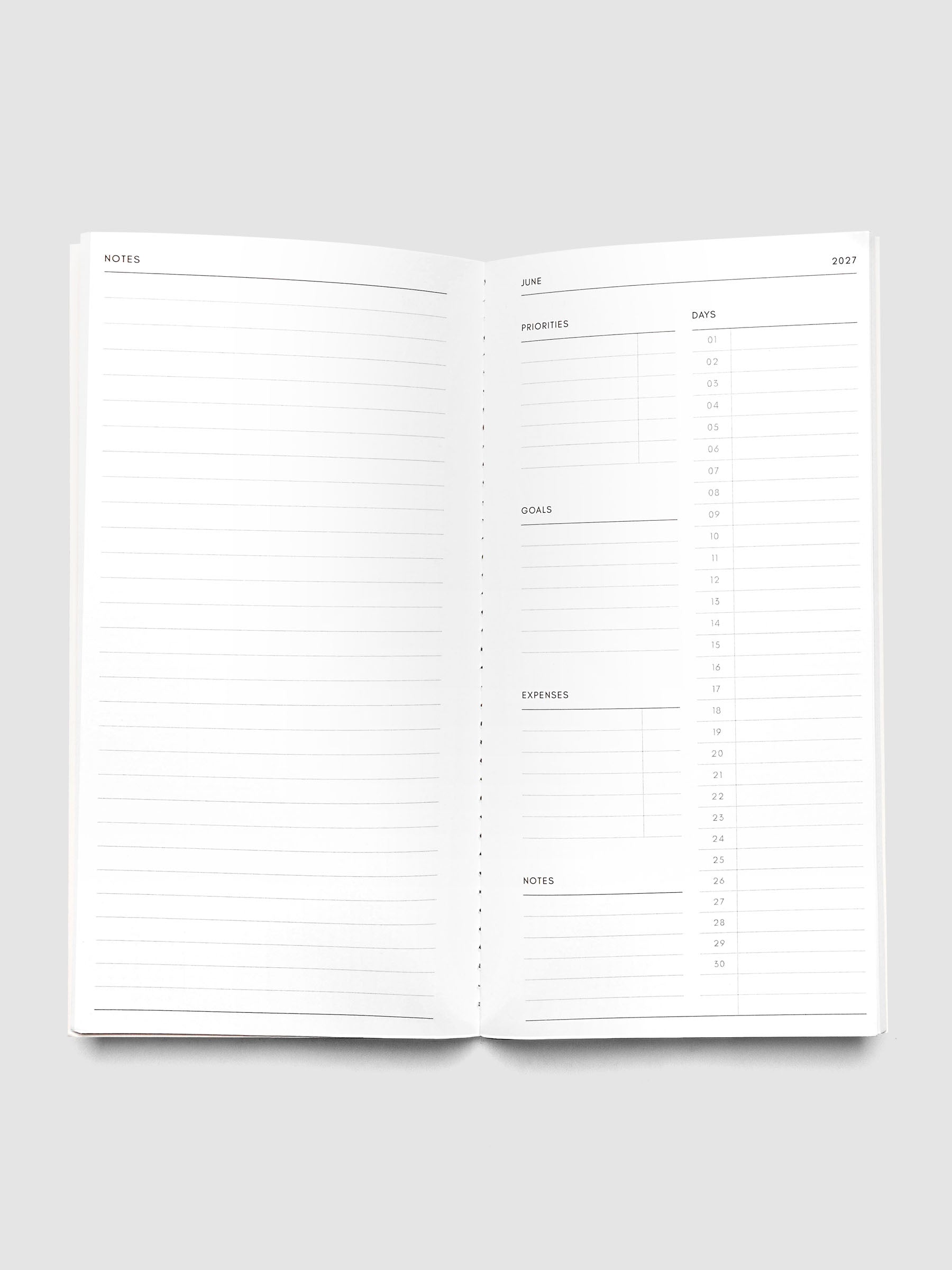 Open 2027 Dated Travel Notebook Monthly in A5 Slim size showing the full monthly overview spread, with a notes page on the left and priorities, days, goals, expenses, and a notes section on the right