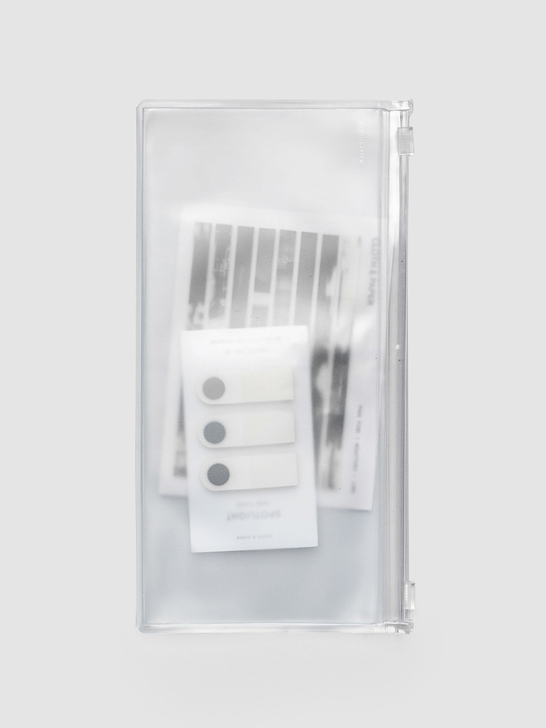 Storage Holder Travel Notebook A5 Slim closed with page pins and page flags inside, frosted clear plastic with silver foil logo