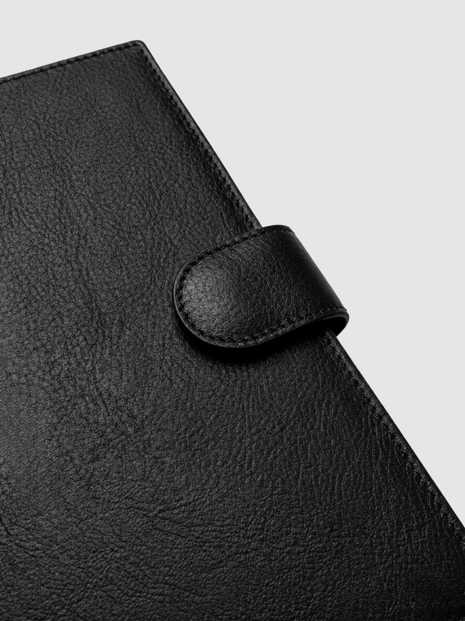 Detail of gold magnetic snap closure securing a black genuine leather A5 planner cover shut