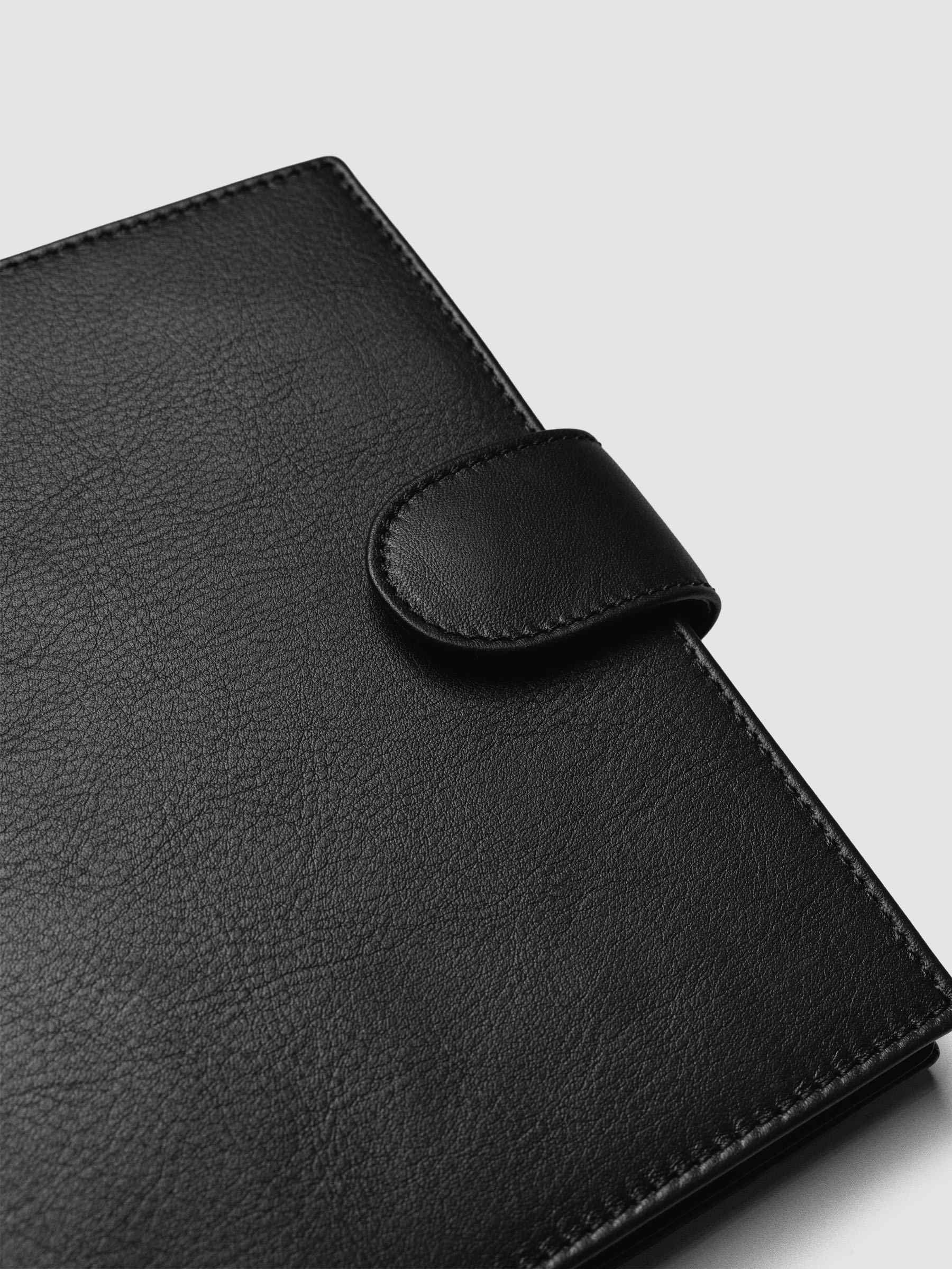 Detail of gold magnetic snap closure securing a black genuine leather Personal Wide 6-ring planner cover shut