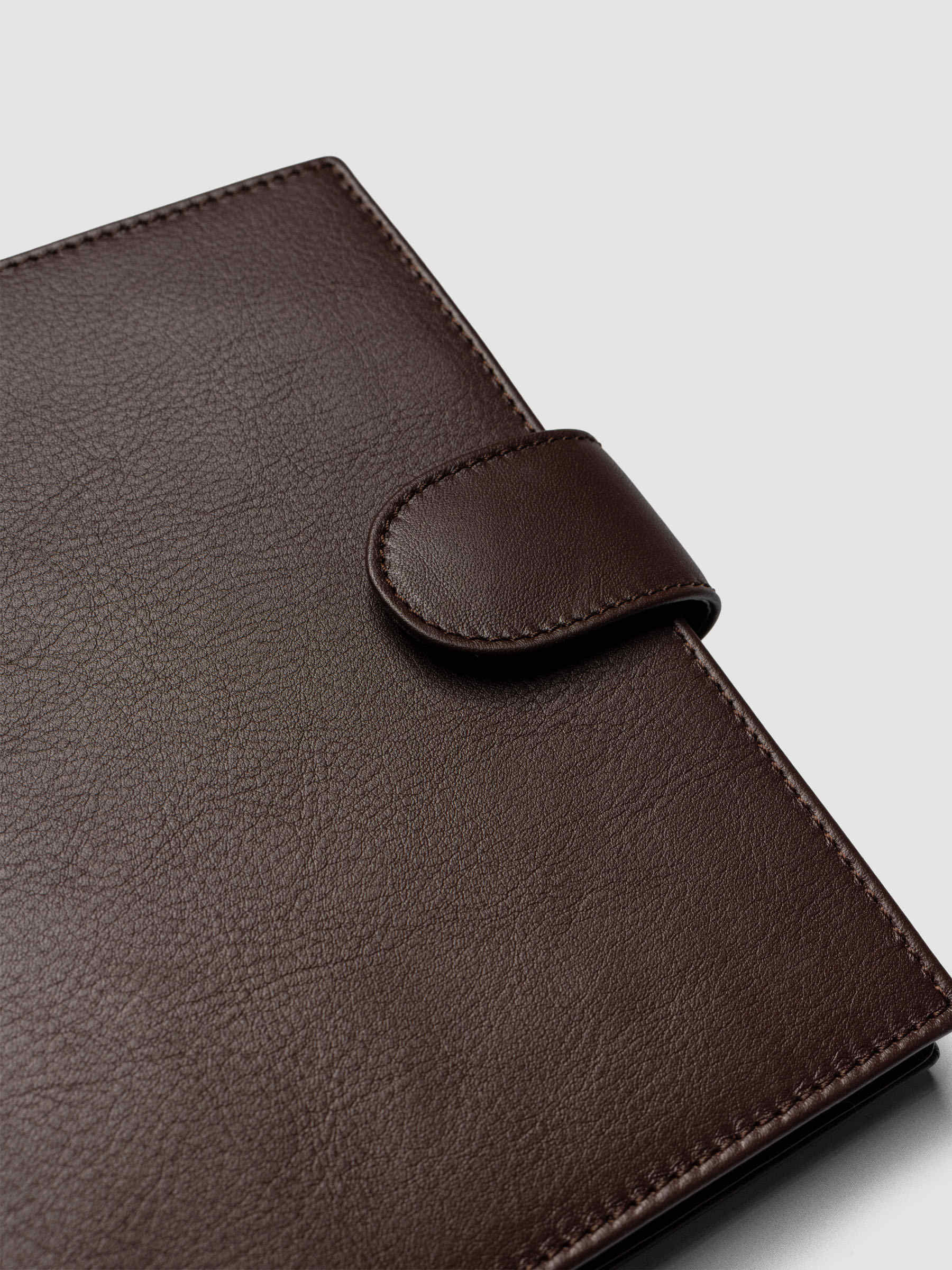 Detail of gold magnetic snap closure securing a dark brown genuine leather Personal Wide 6-ring planner cover shut