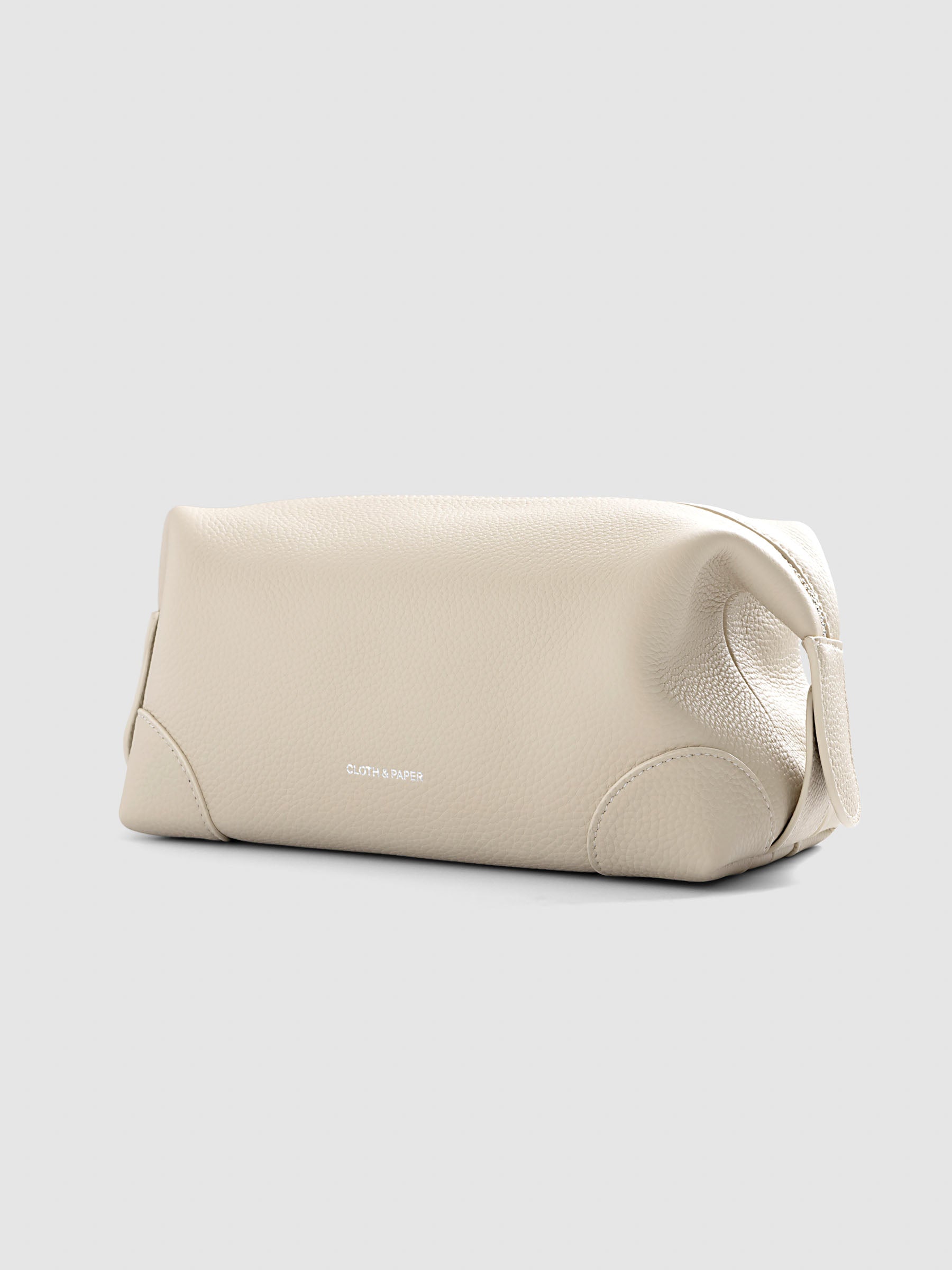 Folded Form Pouch in warm beige pebbled leather, front view, snapped closed with silver foil Cloth & Paper logo centered on exterior