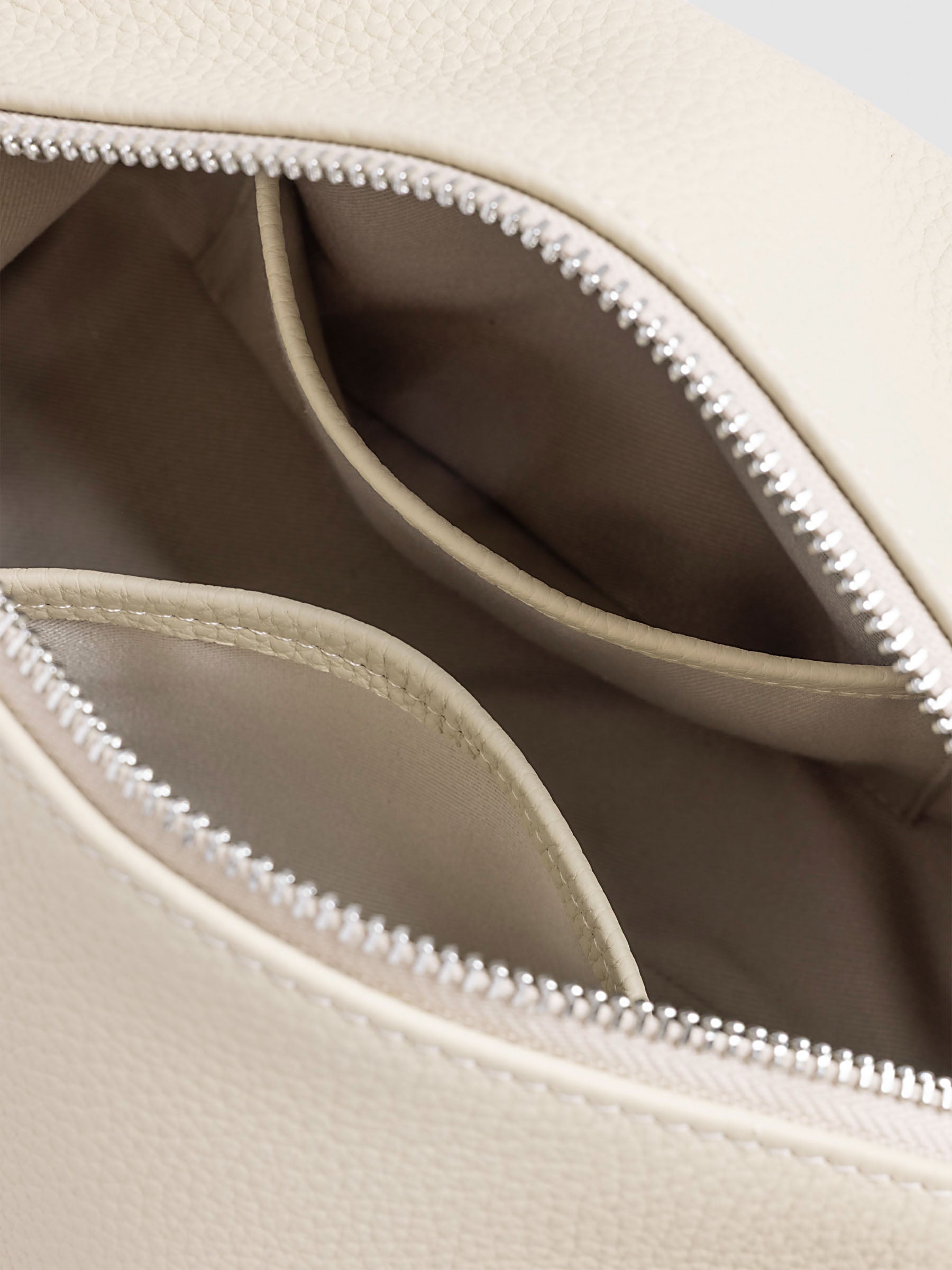 Folded Form Pouch in warm beige pebbled leather, interior close-up showing taupe fabric lining and two open leather-trimmed side pockets