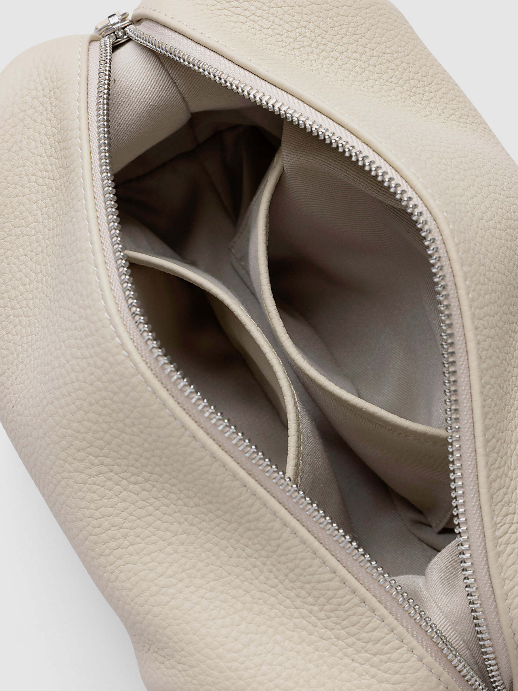Folded Form Pouch in warm beige pebbled leather, top-down angled view, open showing taupe fabric lining and two interior side pockets with silver zipper