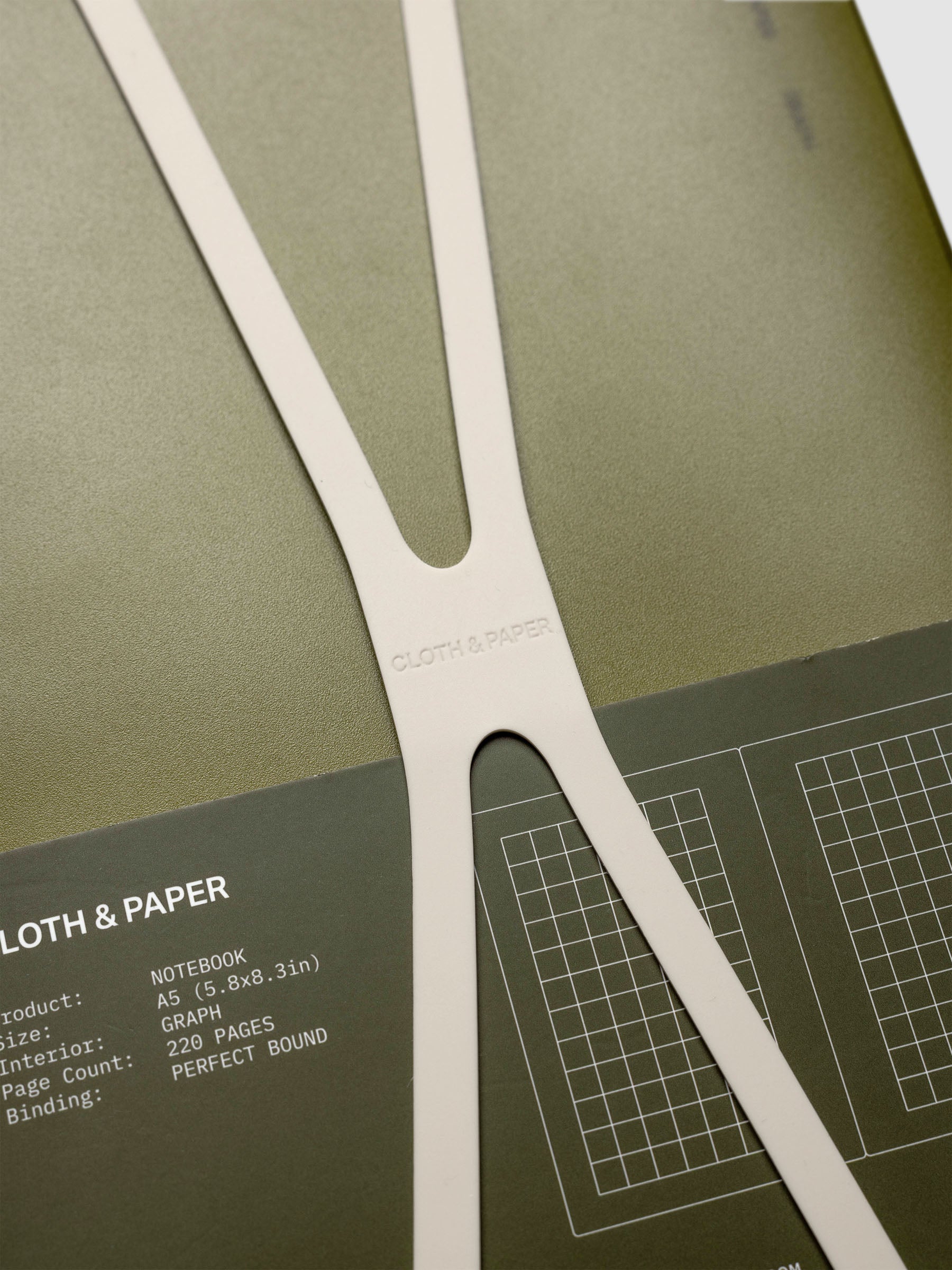Close up of the large, beige planner closure band displaying Cloth & Paper logo imprint.