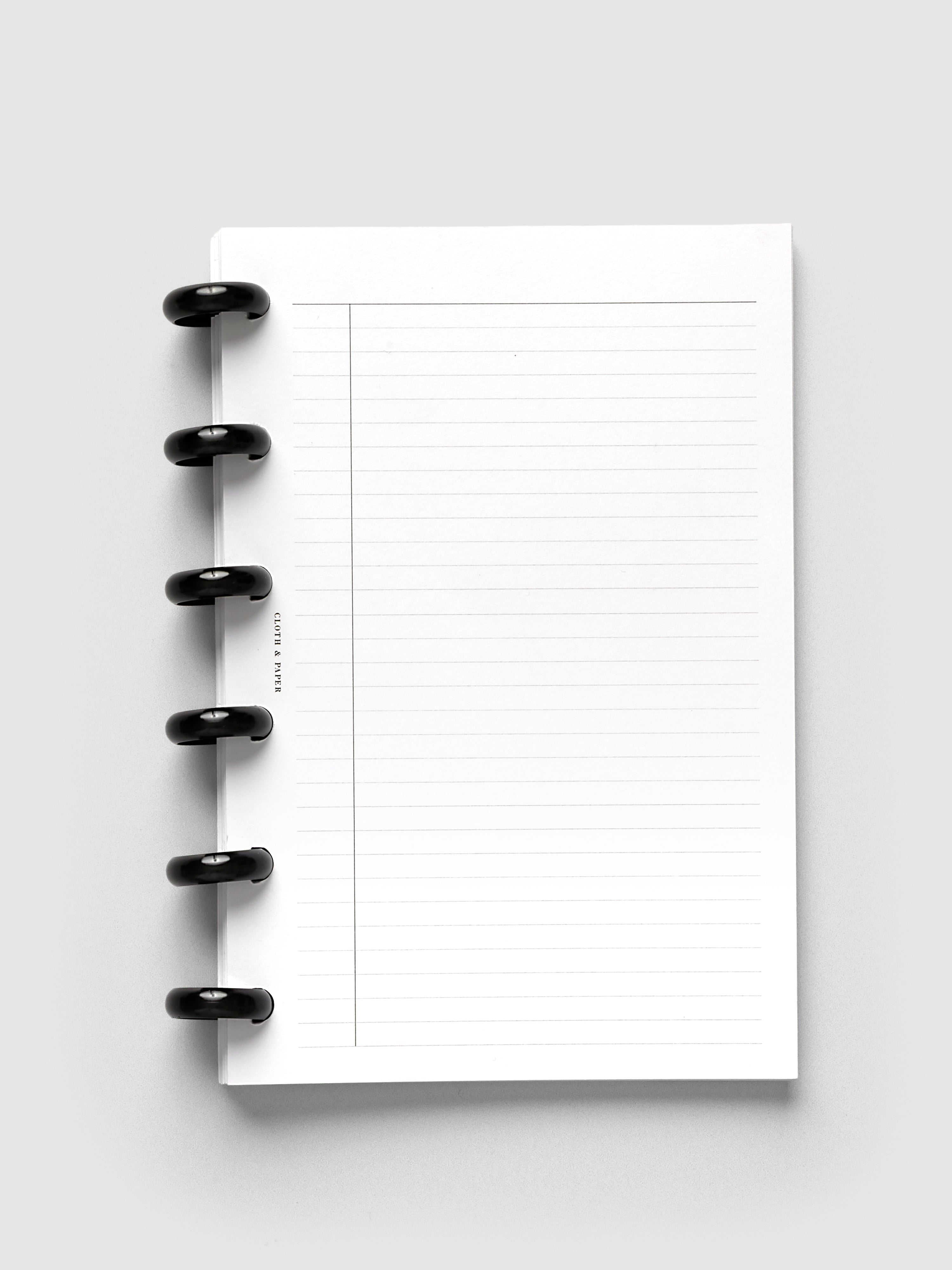 Aluminum Planner Discs | Black, 0.75 Inch, installed on a discbound planner showing lined paper pages with a narrow margin column, front view