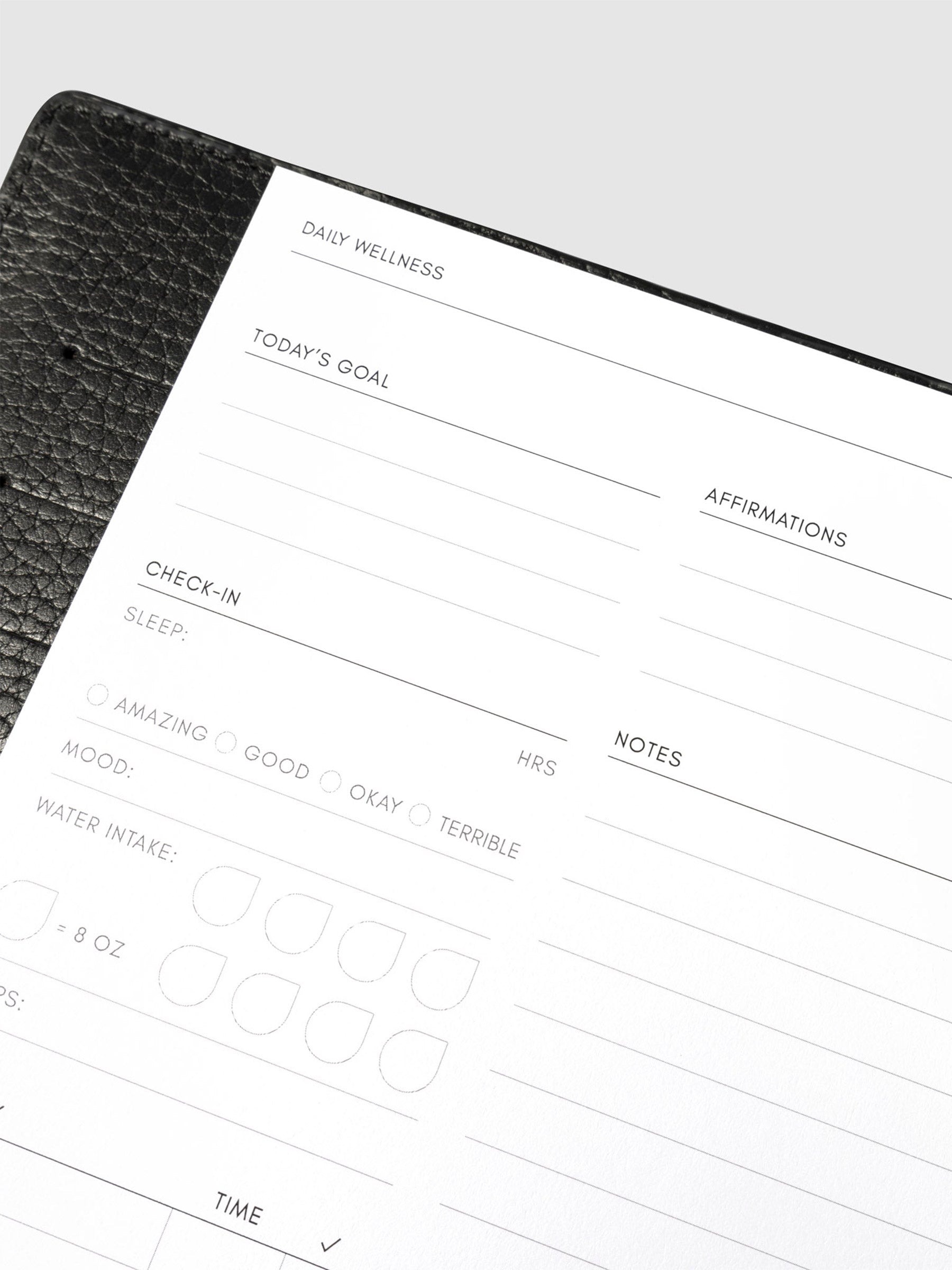 Closeup of daily wellness page inside a black leather planner.
