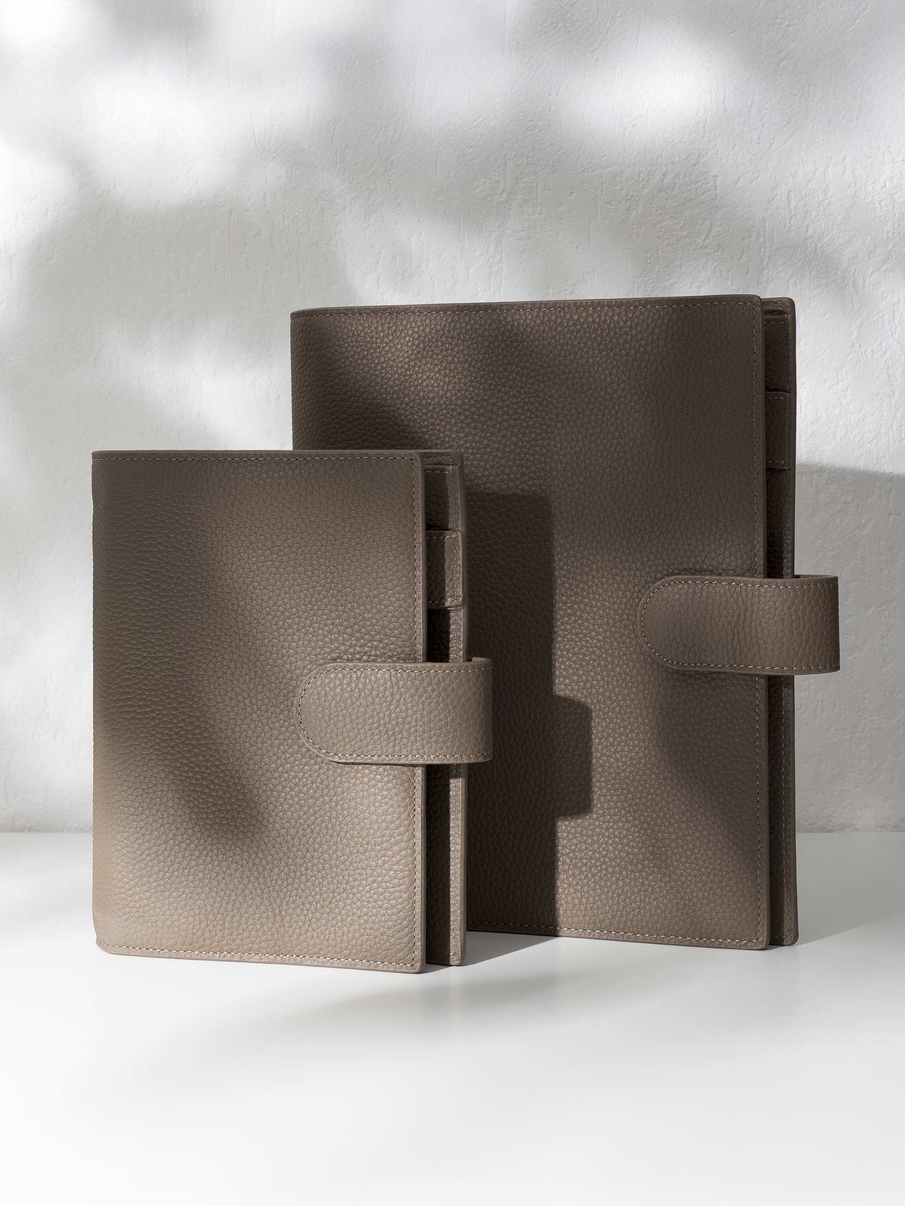 Two brown leather agendas displayed against a shadowed background.