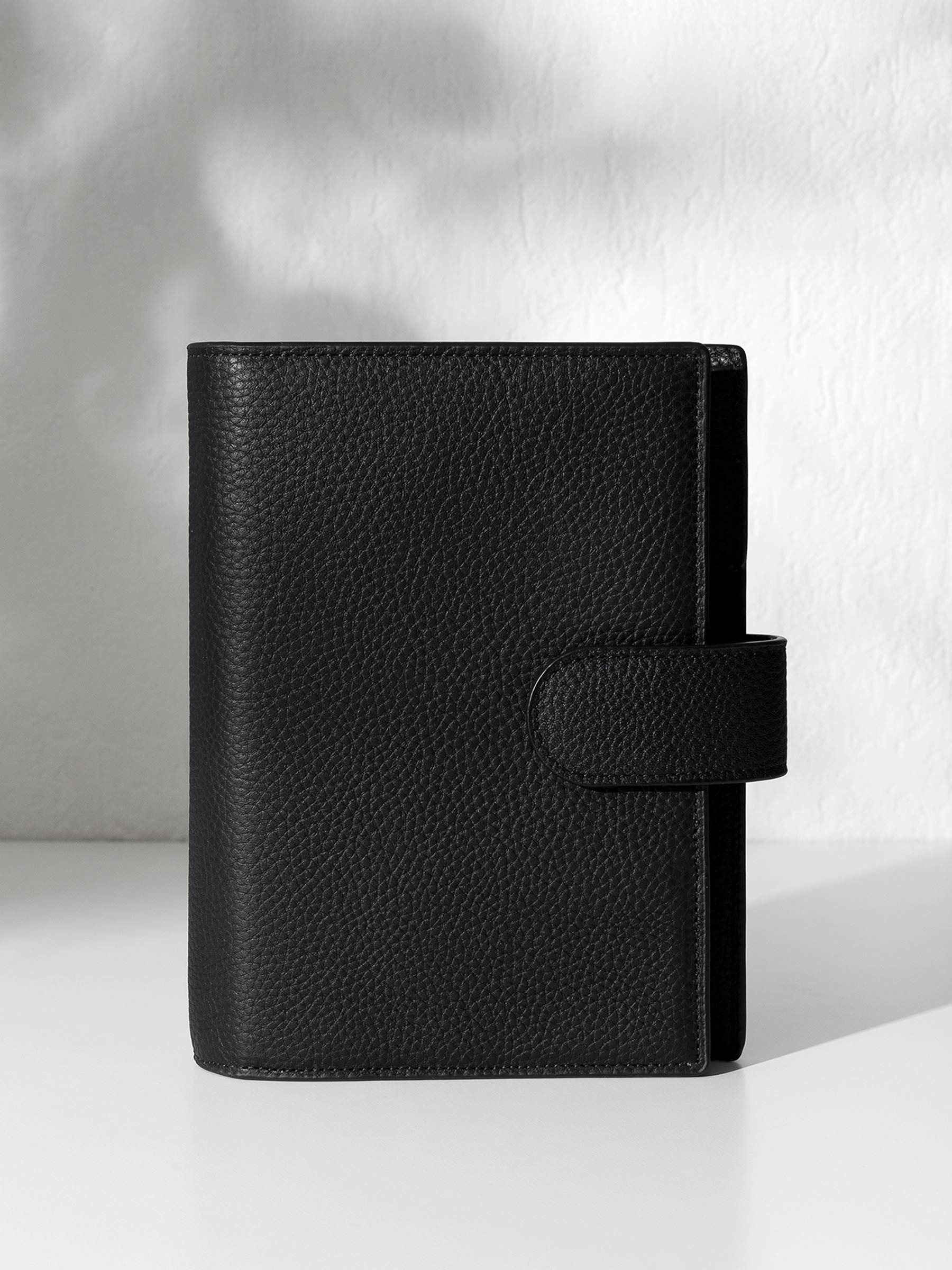 Black leather agenda displayed against a shadowed background.