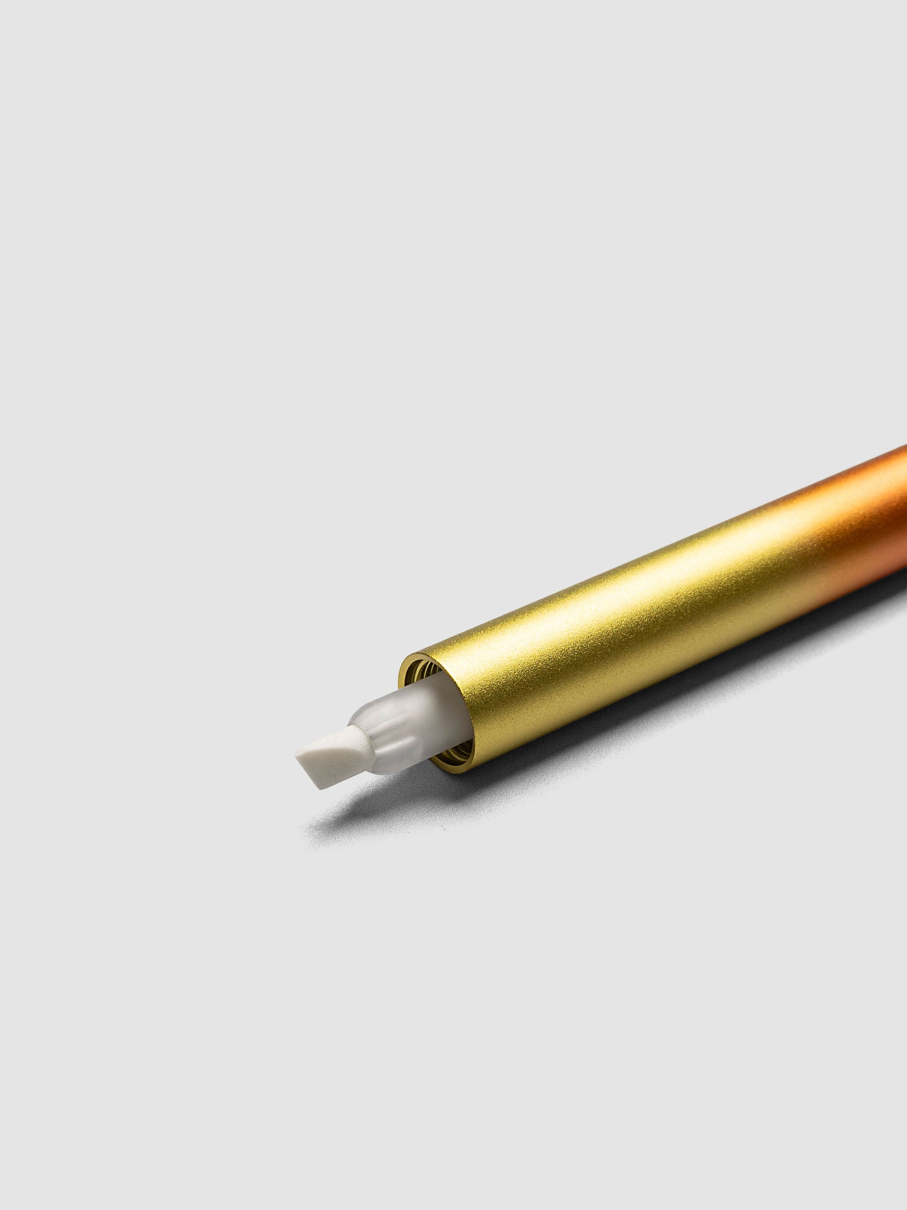 Tom's Studio Ori Refillable Highlighter disassembled into orange cap gold cap orange and gold ombre barrel and two white ink reservoirs with chisel tips