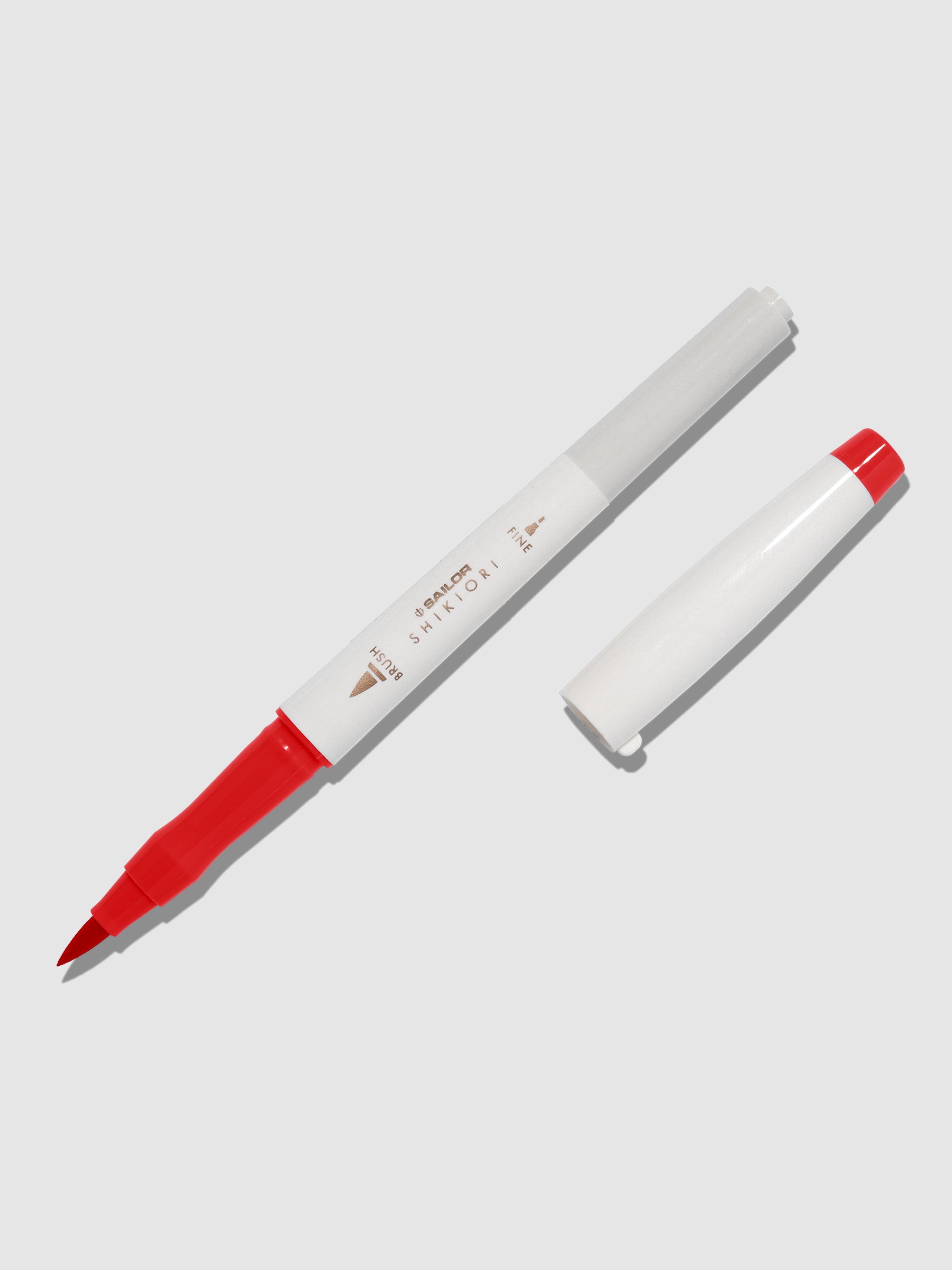 Brush pen displayed on a neutral background. It is uncapped with its brush nib exposed, and the cap lying parallel to the marker. Color pictured is Irori.