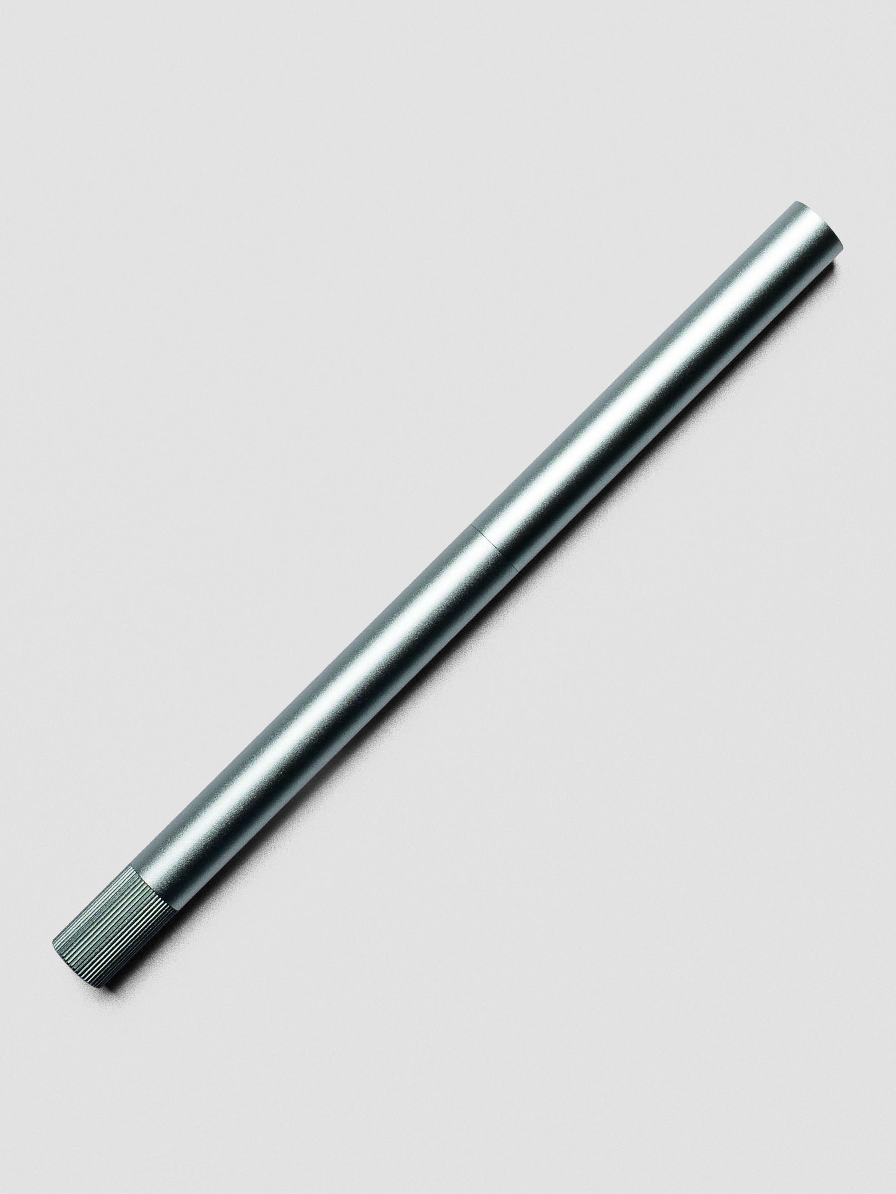 Sage Green Lumos Pro Duo Tip Pen resting diagonally on an open notebook, capped.