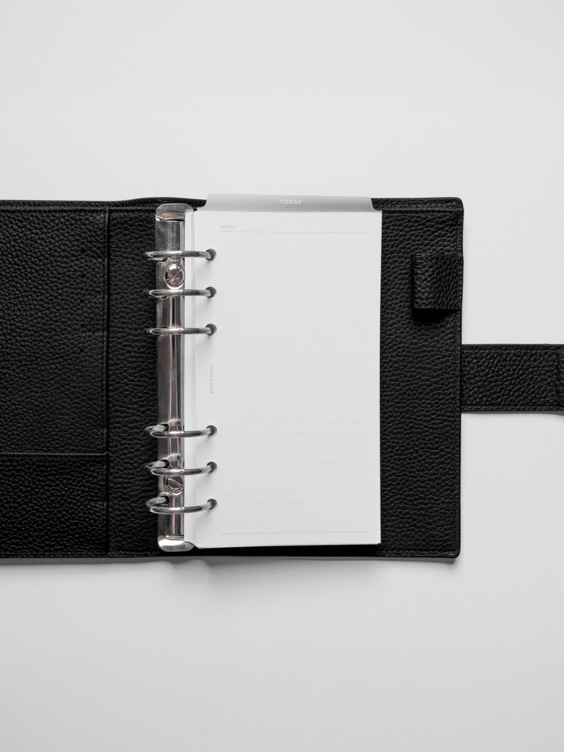 White foil divider displayed in a black leather planner.