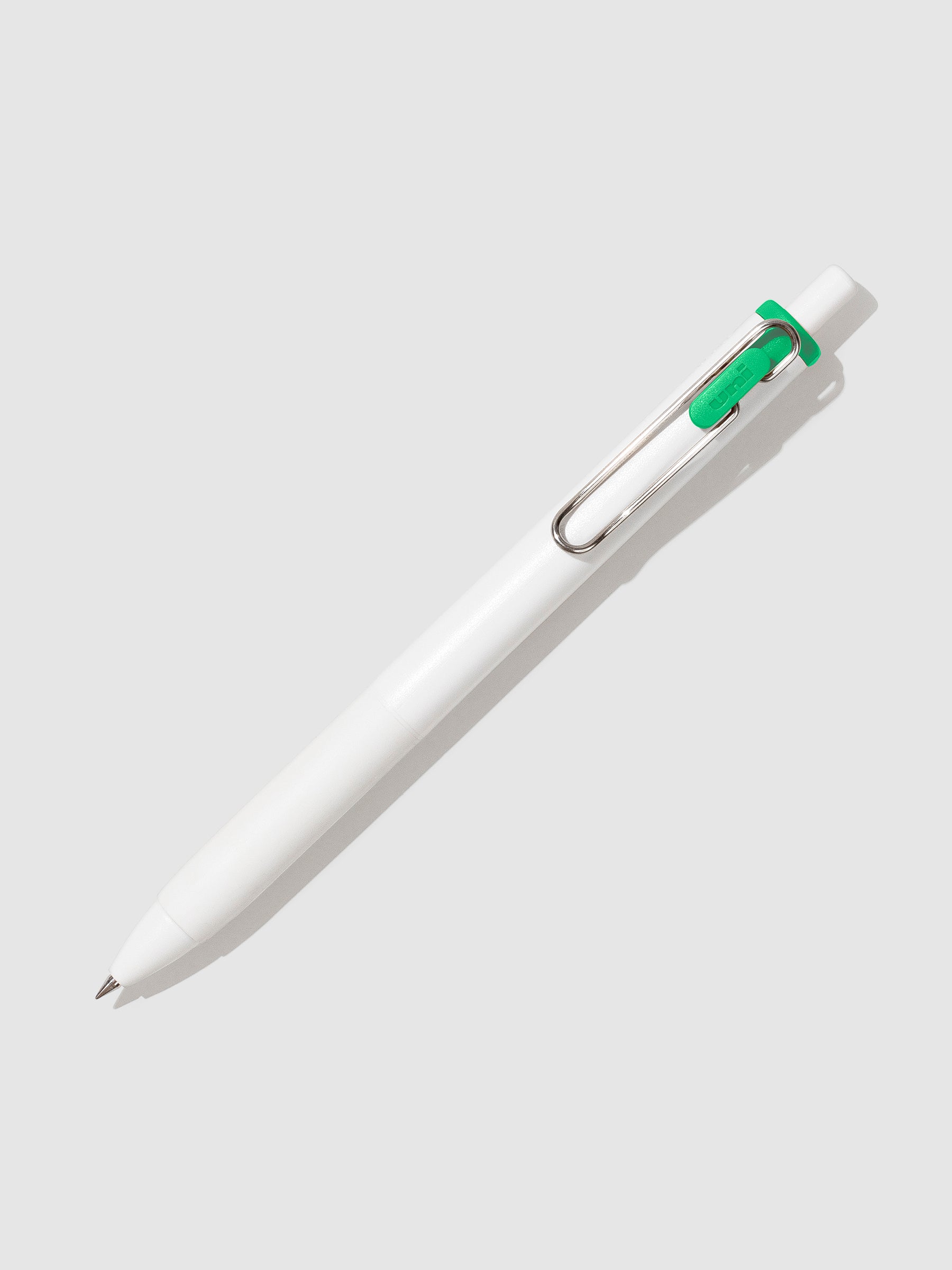Uni-ball One Gel Pen, Green, Cloth and Paper. Pen tilted slightly to the right on a neutral background.