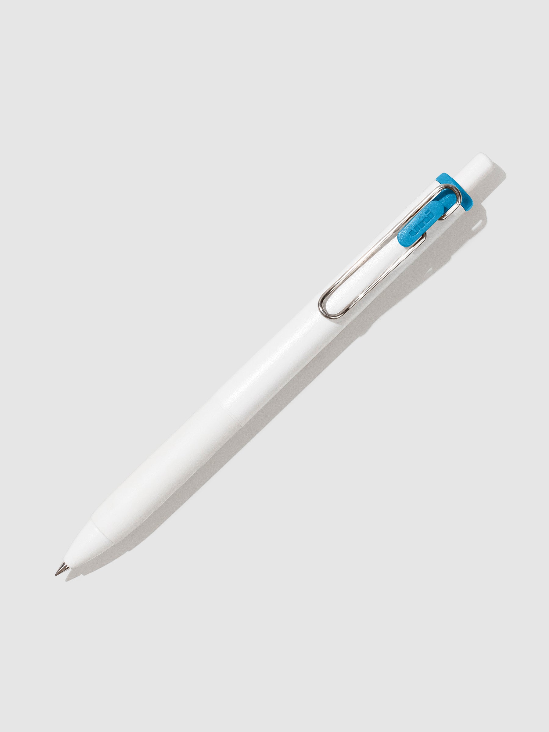 Uni-ball One Gel Pen, Sunny Day Blue, Cloth and Paper. Pen tilted slightly to the right on a neutral background.
