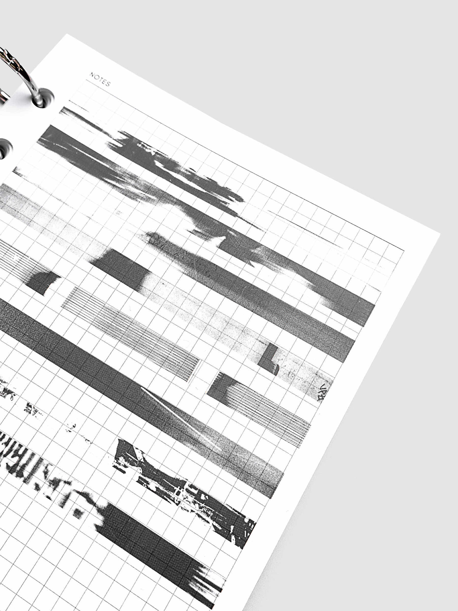Page Pins | Long | Negatives, close-up of film negative-style transparent grey page pins on graph insert pages in a 6-ring planner