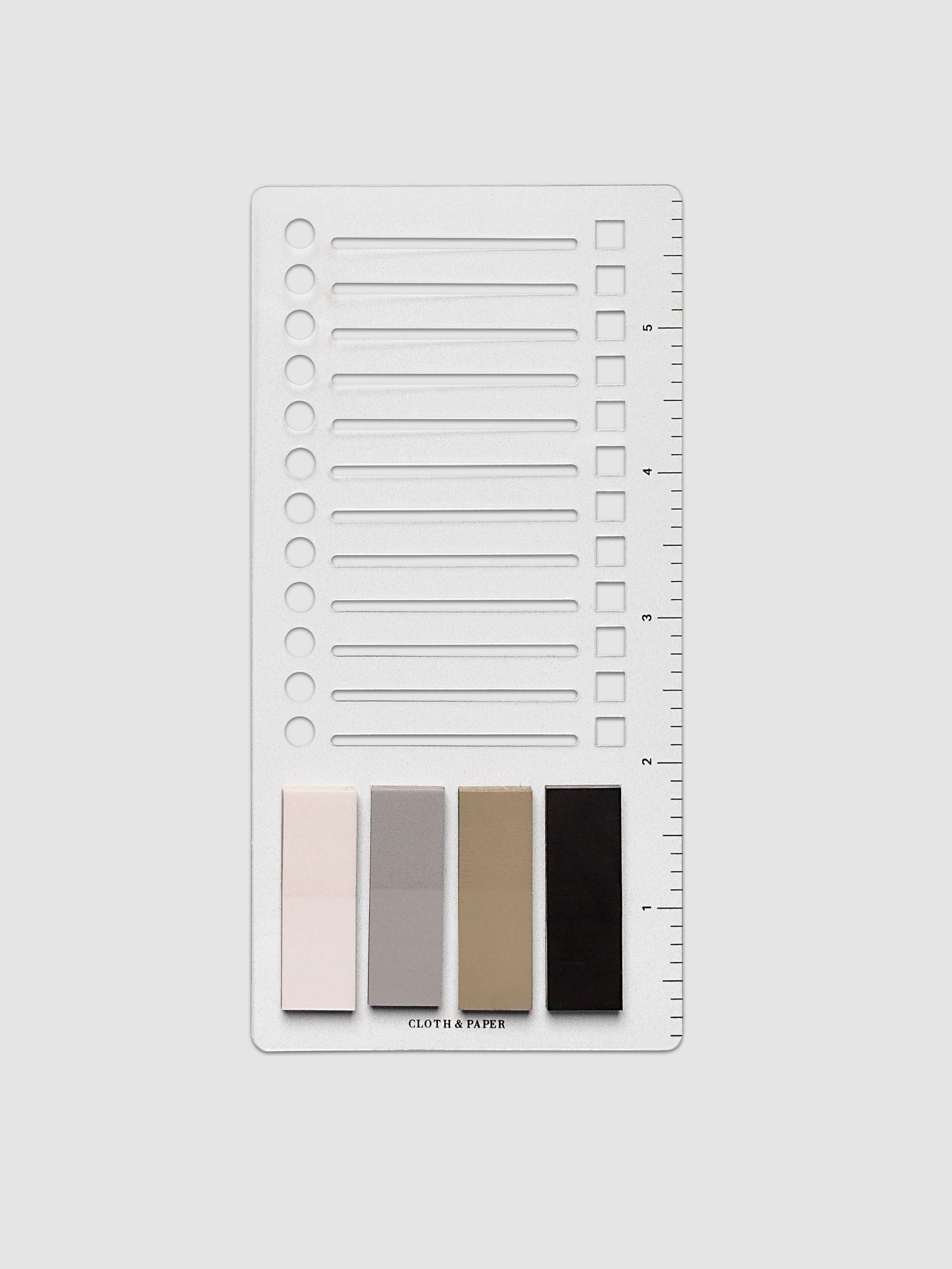Stencil Page Flag Set, full product view showing clear plastic stencil with circle, line, and square cutouts and ruled edge, with four page flag colors fanned below: blush pink, light gray, warm tan, and near-black