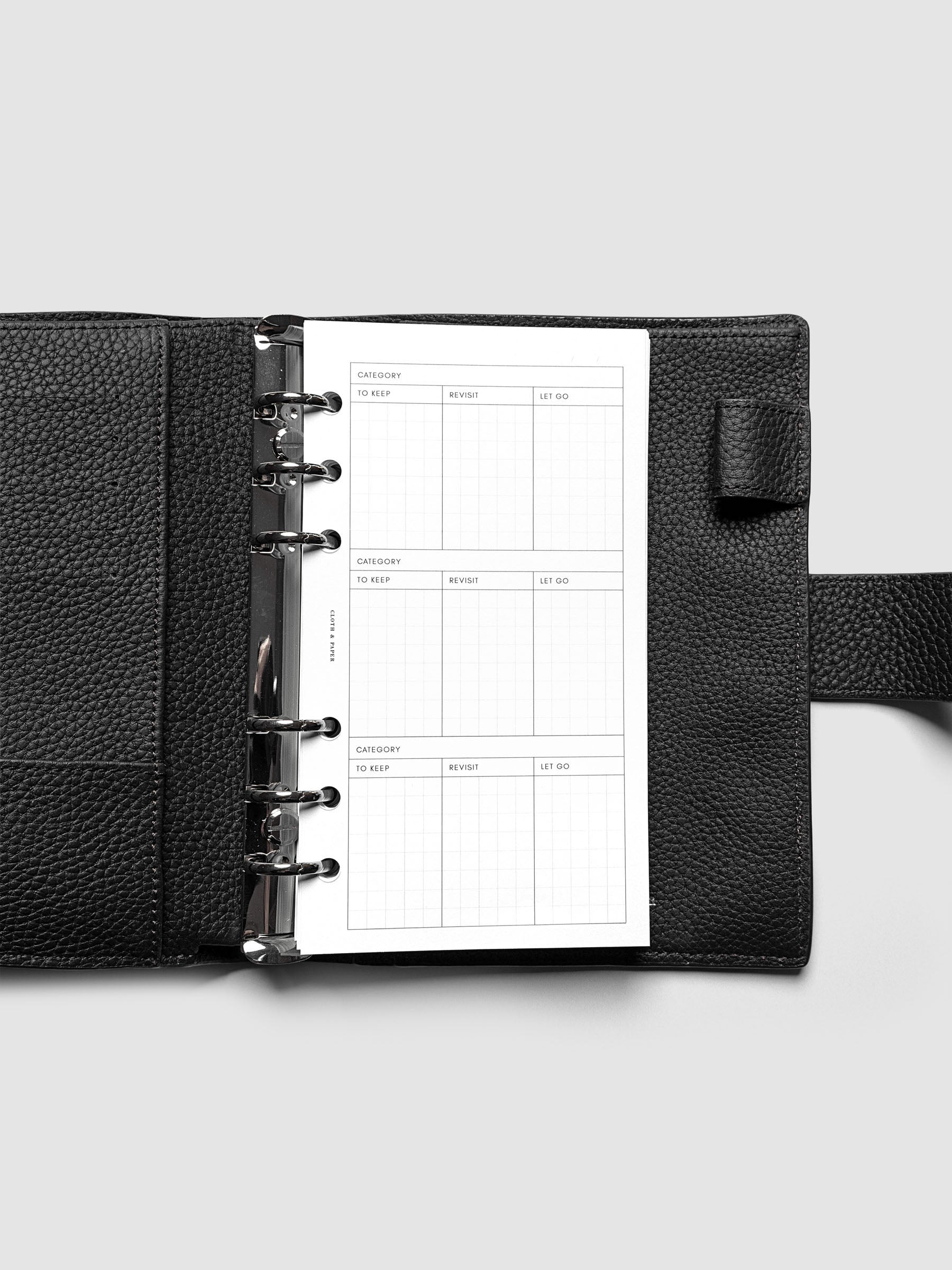 Declutter Planner Inserts in size Personal shown ring bound in a black leather agenda.