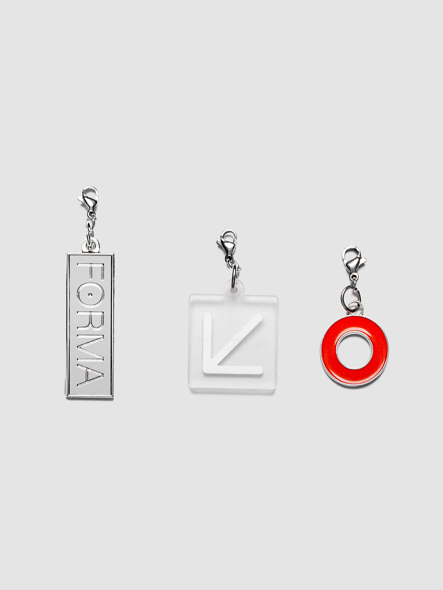 Travel Notebook Charms set of three including SPOTLIGHT charm in deep orange enamel, FORMA charm in embossed silver metal, and ARROW charm in translucent white plastic