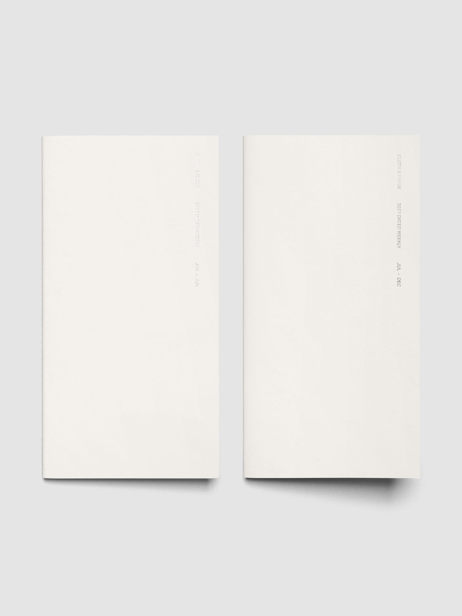Both 2027 Dated Travel Notebooks in A5 Slim size displayed side by side, showing the off-white covers with silver foil text for the Jan–Jun and Jul–Dec volumes