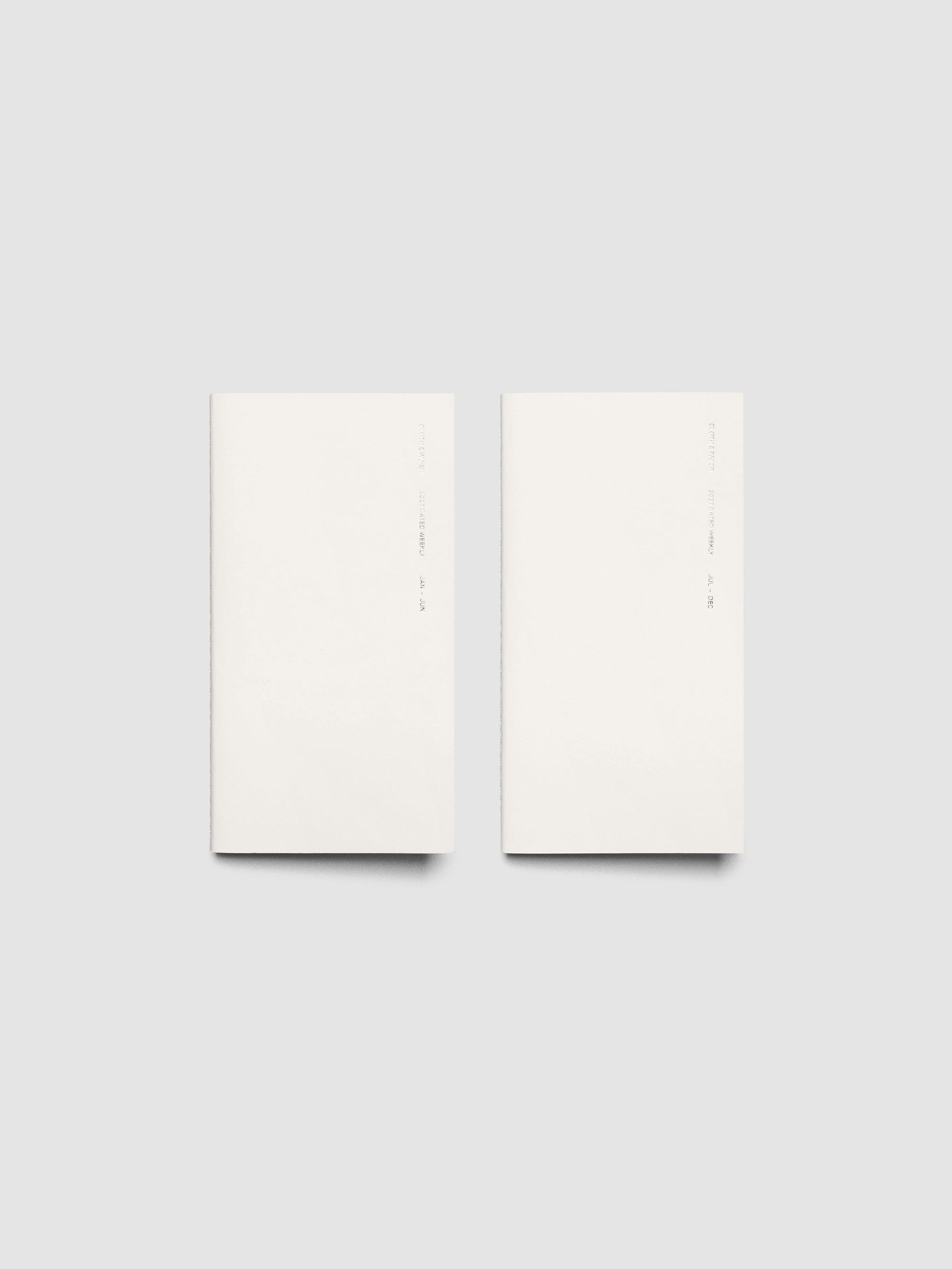 Both 2027 Dated Travel Notebooks in Pocket Plus size displayed side by side, showing the off-white covers with silver foil text for the Jan–Jun and Jul–Dec volumes