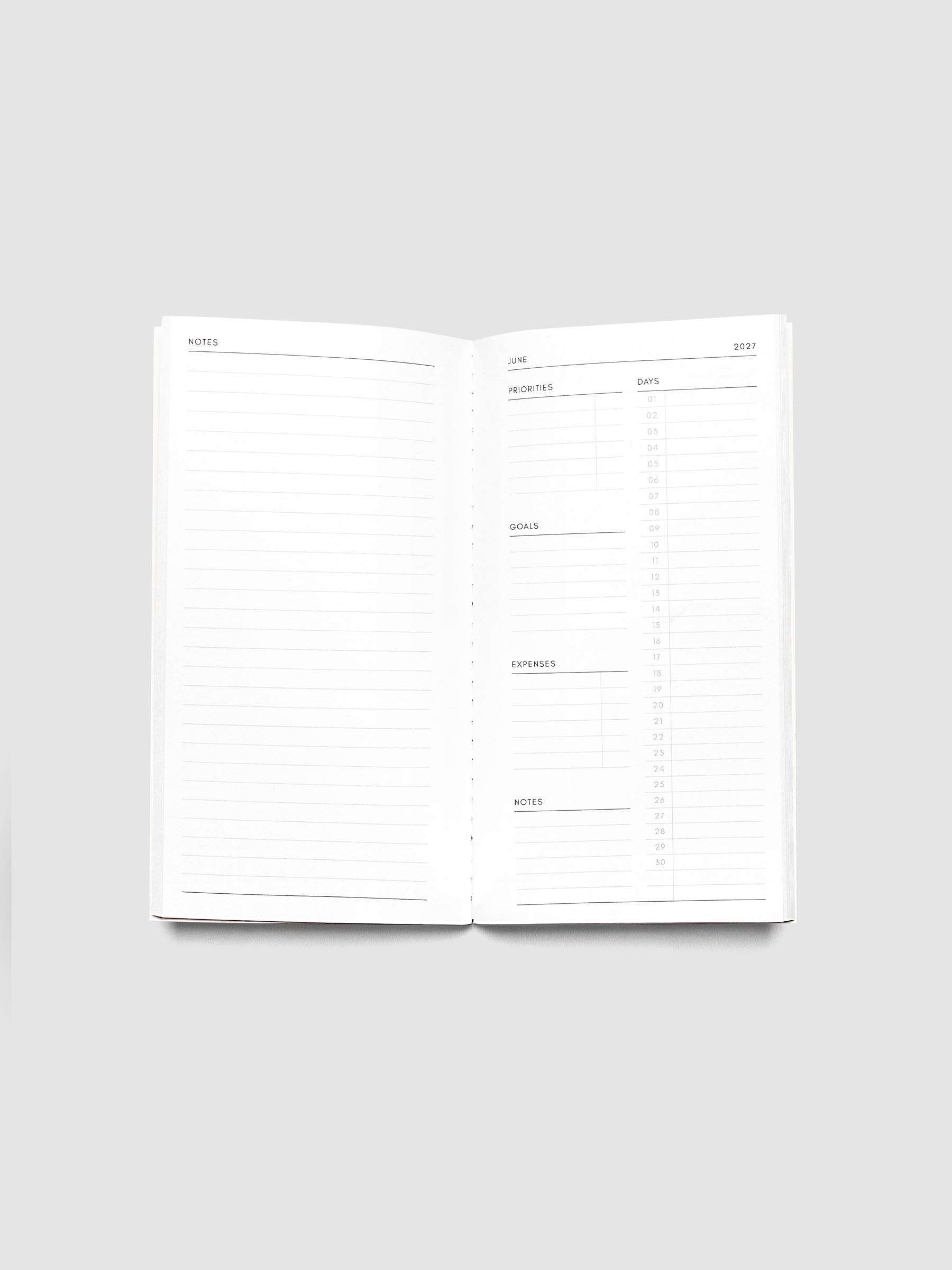 Open 2027 Dated Travel Notebook Monthly in Pocket Plus size showing the full monthly overview spread, with a notes page on the left and priorities, days, goals, expenses, and a notes section on the right