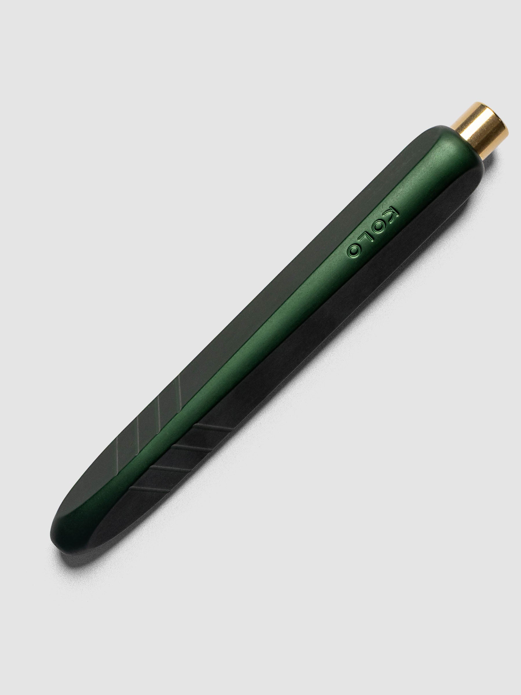 Kolo Tino Ballpoint Pen in Anodized Aluminum Verdant, a deep forest green barrel with gold top button, retracted, angled view