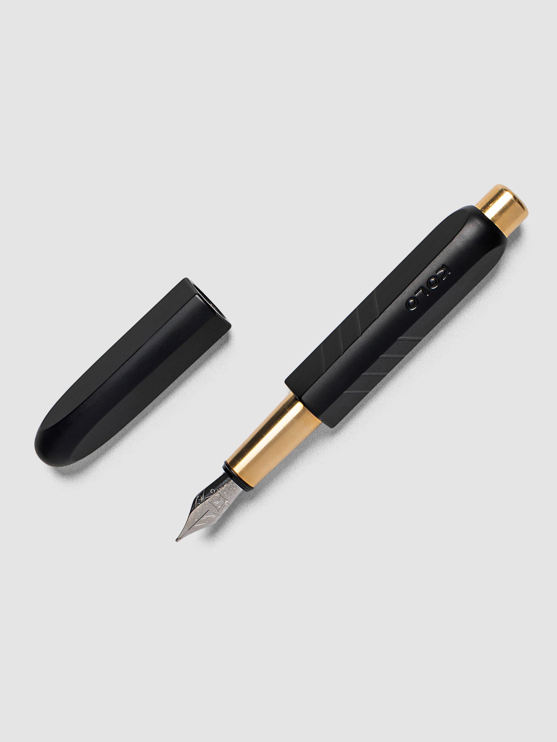 Kolo Tino Fountain Pen in Anodized Aluminum Noir, a matte black barrel with gold accents and silver medium nib shown with cap off, full pen view