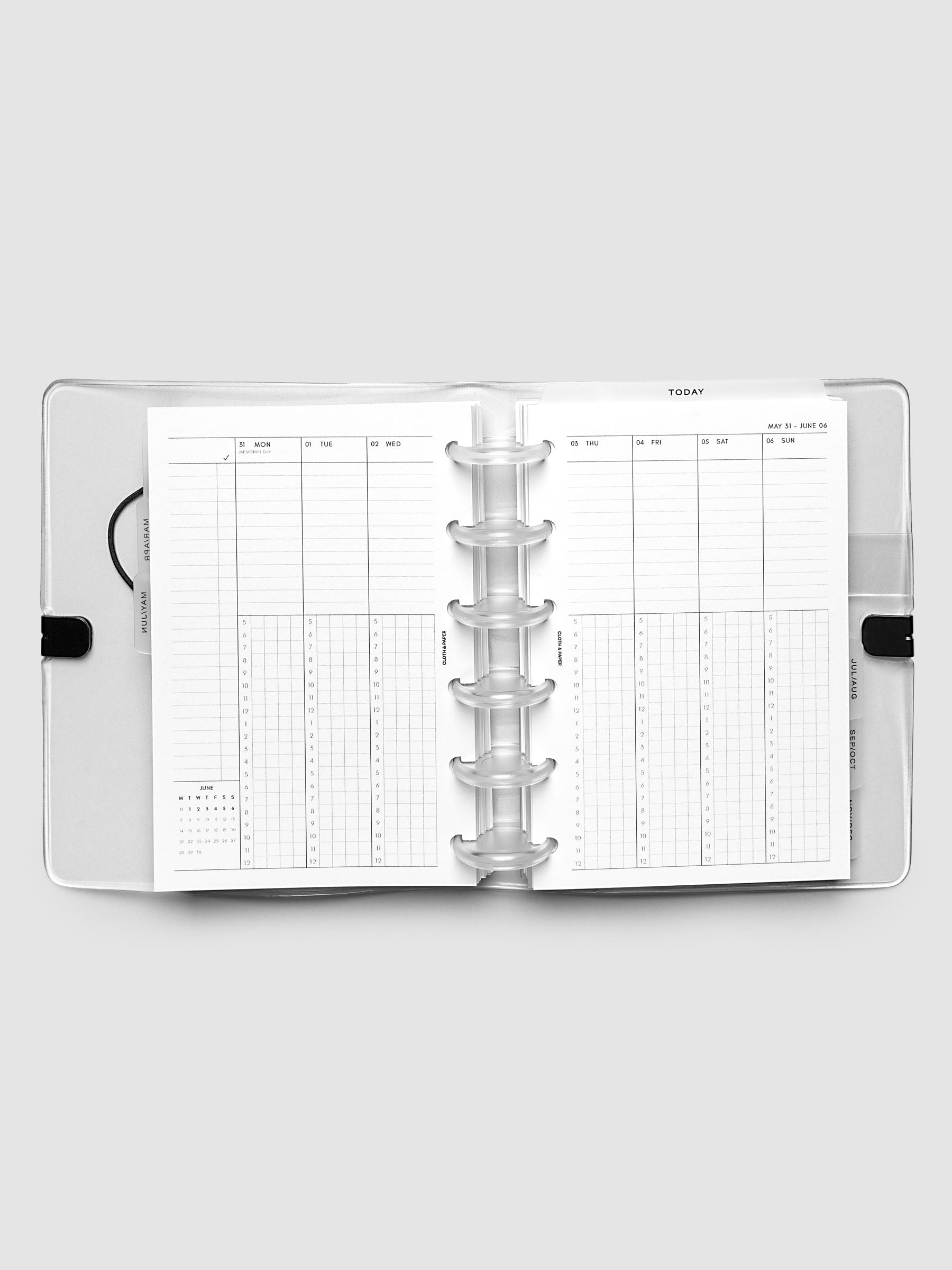 Flat lay of an open planner with clear 6-disc binding at the center, a Monday through Sunday weekly time block spread across two facing pages with task lists, hourly grids, and a mini monthly calendar, CP Petite 6-Disc Punch size