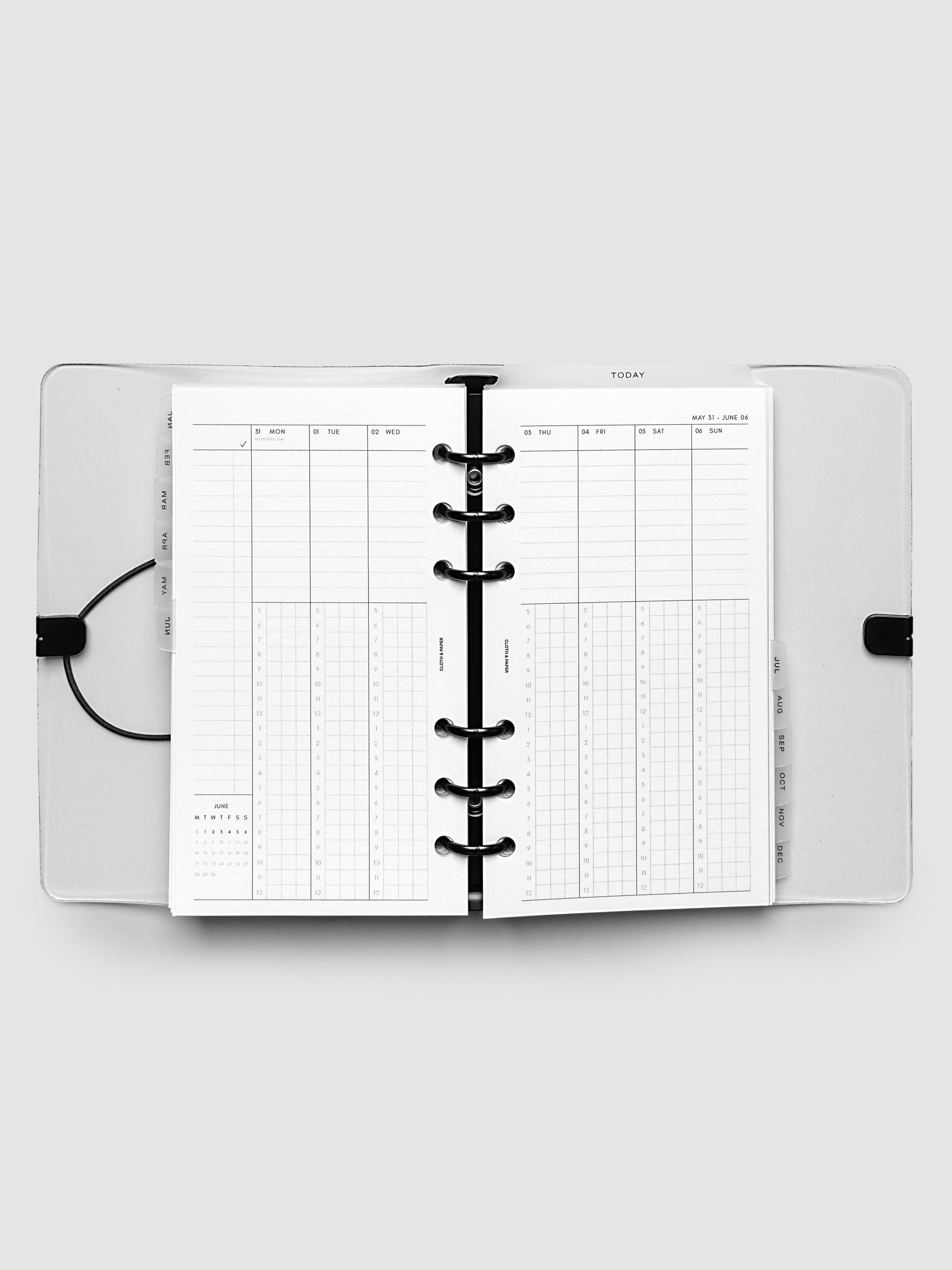 Flat lay of an open planner with black 6-ring binding at the center, a Monday through Sunday weekly time block spread across two facing pages with task lists, hourly grids, and a mini monthly calendar, Personal 6-Ring Punch size