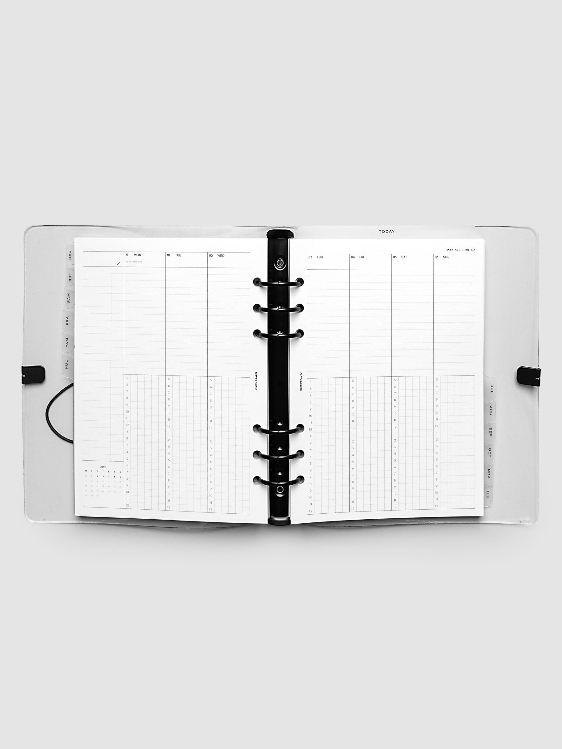 Flat lay of an open planner with black 6-ring binding at the center, a Monday through Sunday weekly time block spread across two facing pages with task lists, hourly grids, and a mini monthly calendar, A5 6-Ring Punch size