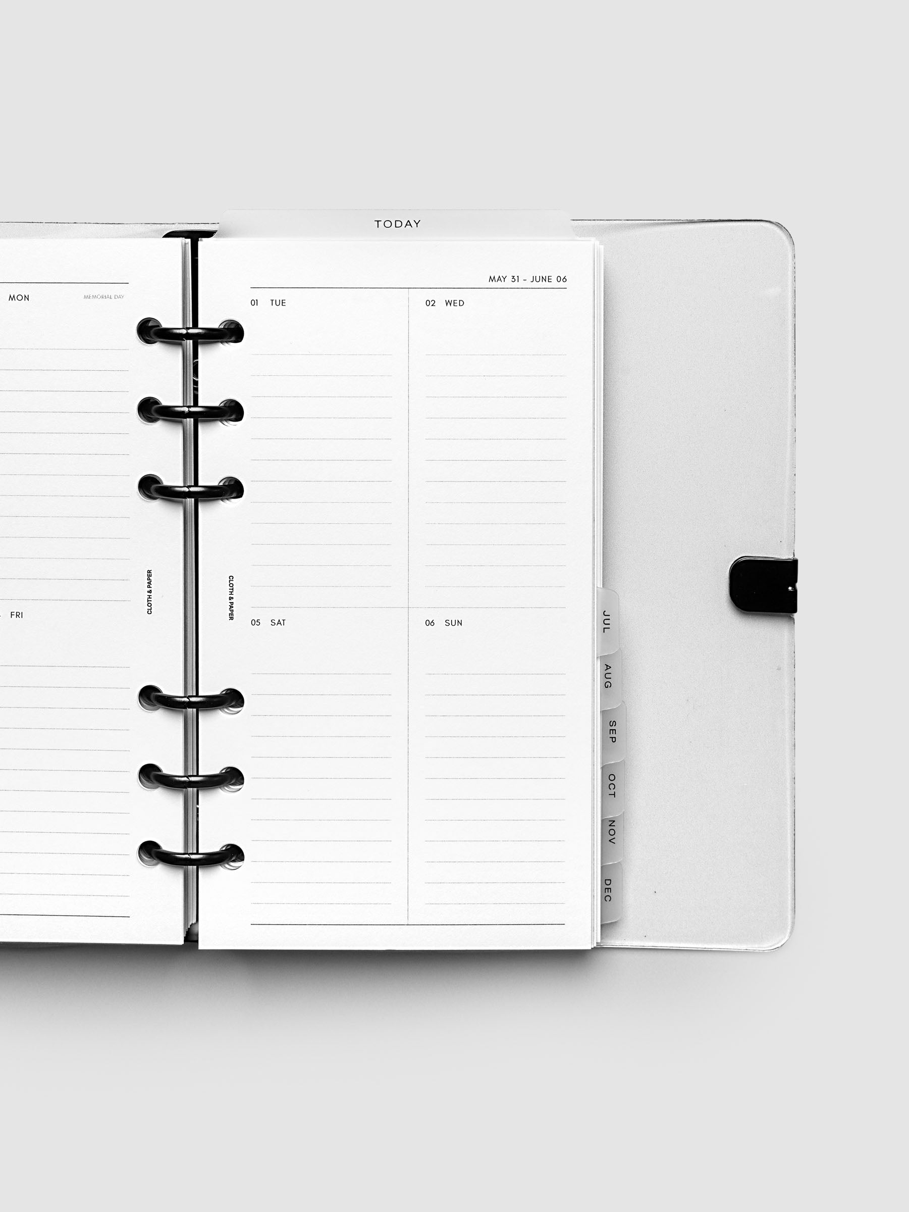 Close-up of an open planner with black 6-ring binding, weekly vertical spread showing Tuesday through Sunday in a two-column grid with lined daily sections, tabbed monthly dividers visible at the edge, Personal 6-Ring Punch size