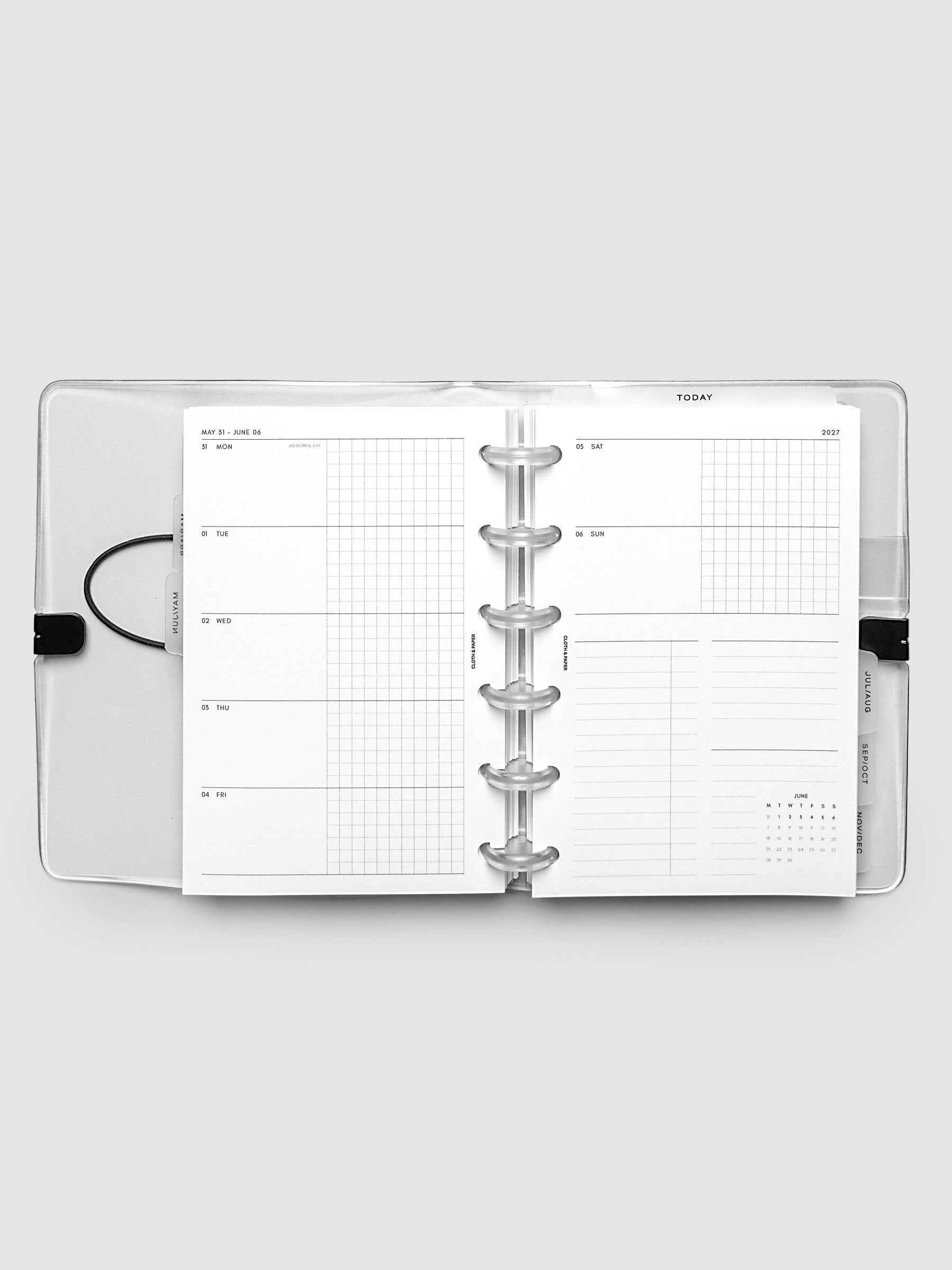 Flat lay of an open planner with clear 6-disc binding at the center, a Monday through Sunday weekly horizontal spread across two facing pages with a tasks and notes section and mini calendar, CP Petite 6-Disc Punch size