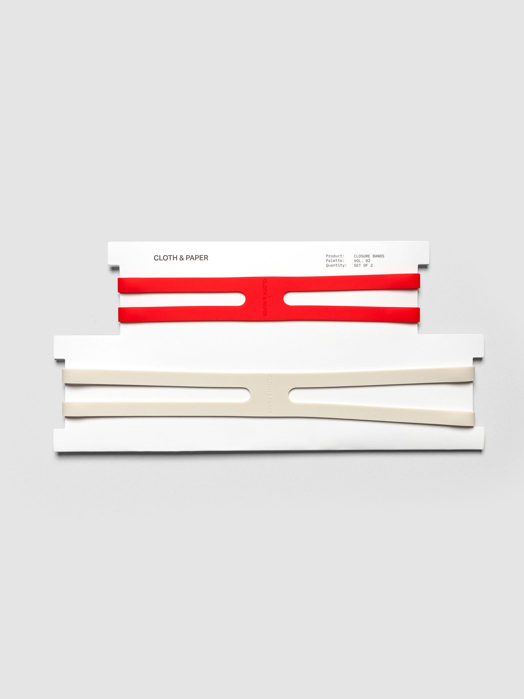 Planner Closure Bands Vol. 2 shown in packaging. Includes 1 small red band and a large beige band in x shape.