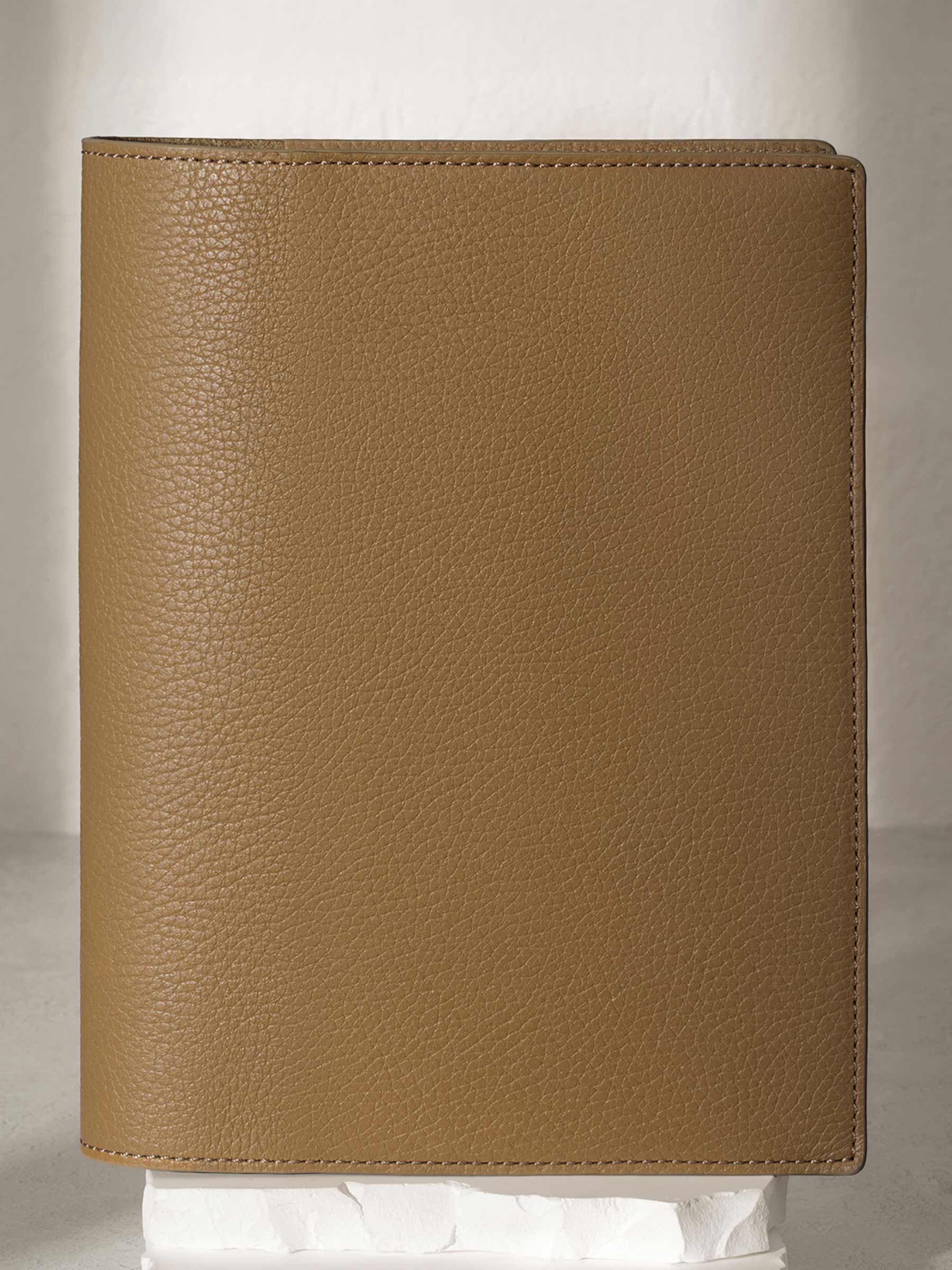 Large Catalonia folio displayed on a white stone pedestal. The background is a natural textured off-white material, and a spotlight behind the folio highlights its placement.